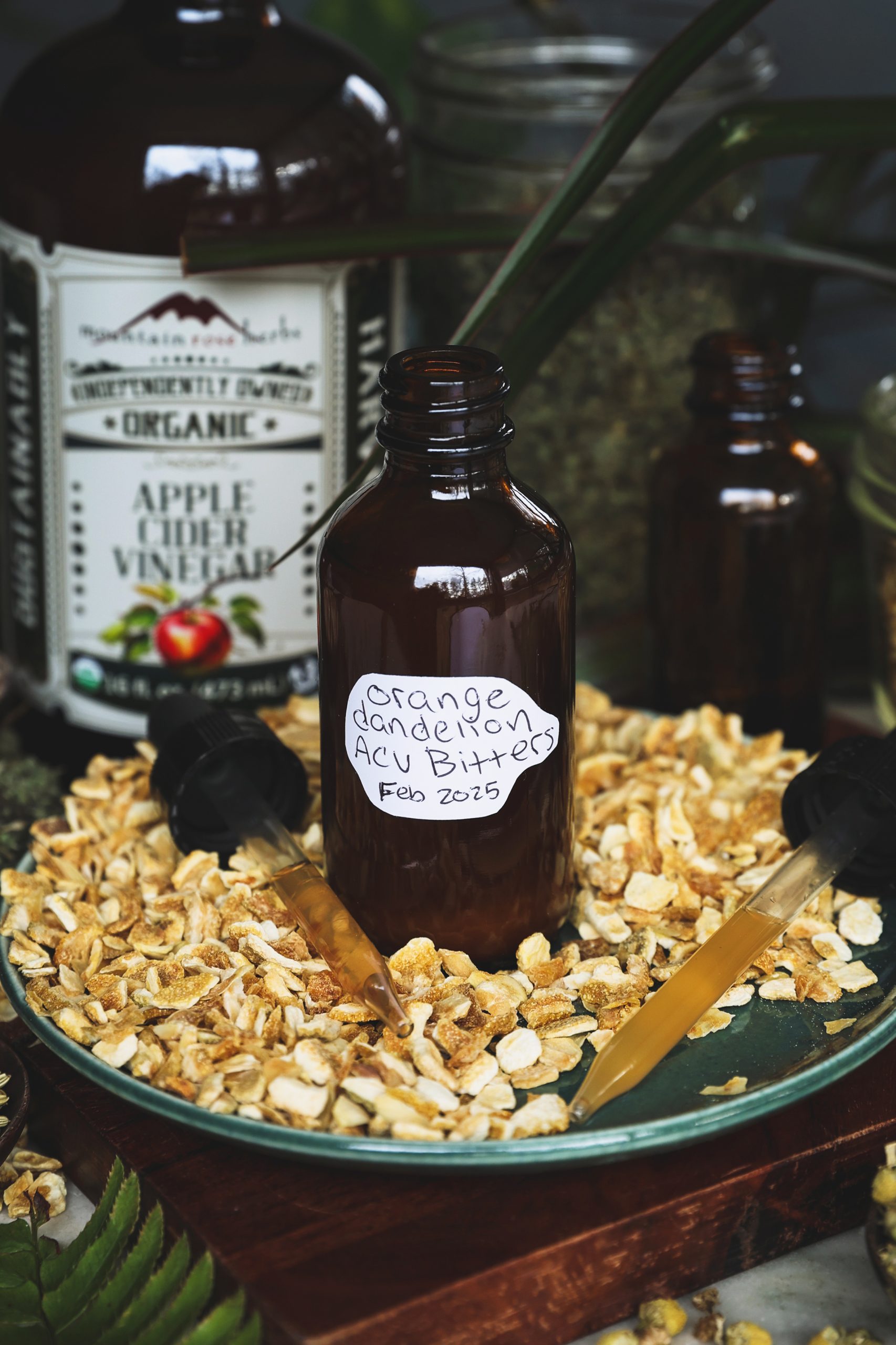 A dropper bottle of vinegar bitters surrounded by dried orange peel and droppes