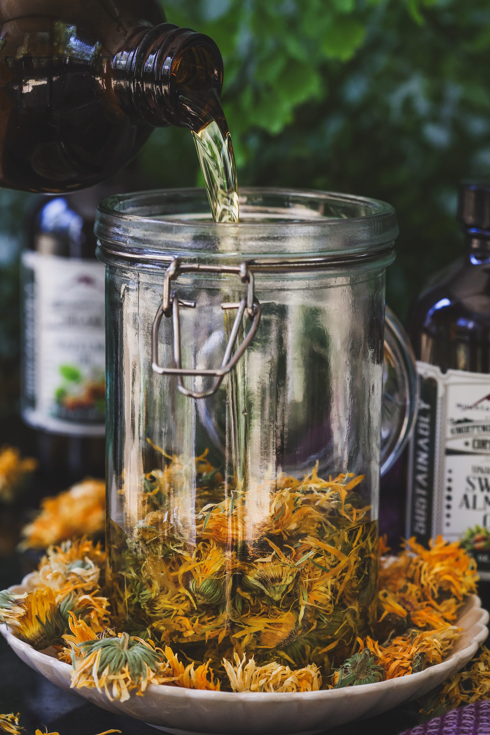 Oil being poured into a jar of dried calendula flowers