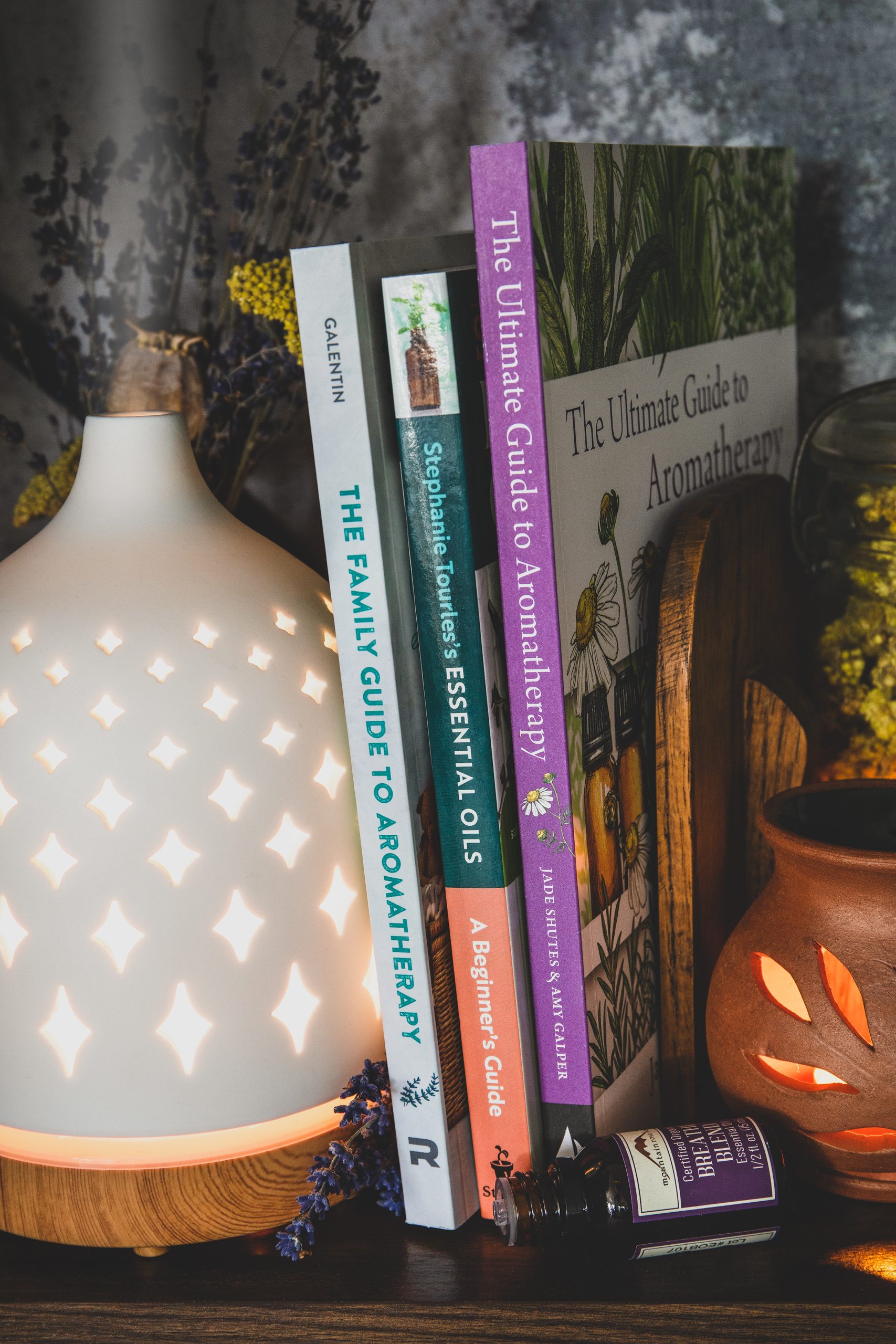 Best books on aromatherapy- set on shelf with diffuser and essential oil bottles