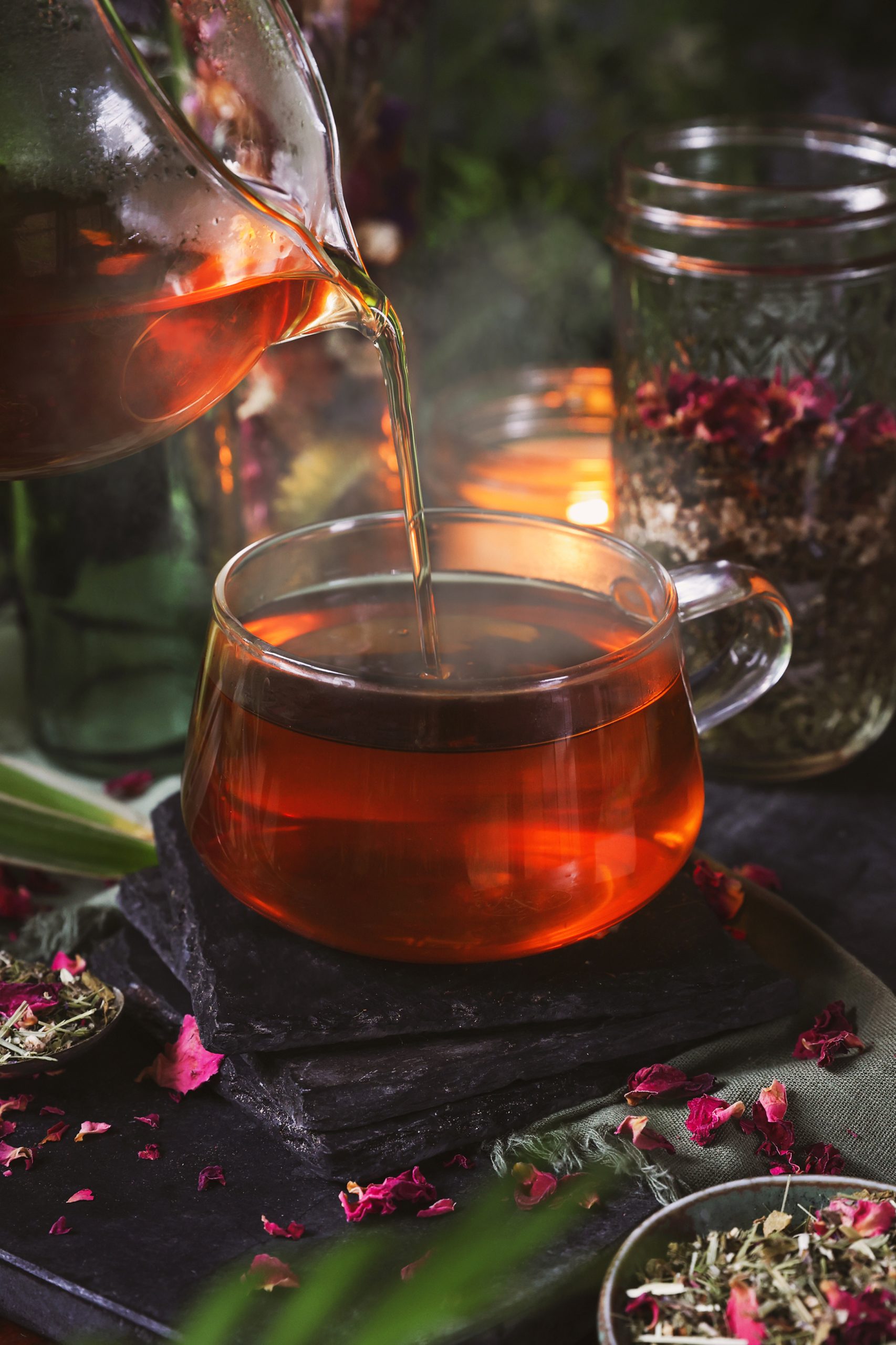 A steamy herbal tea is poured into a glass mug