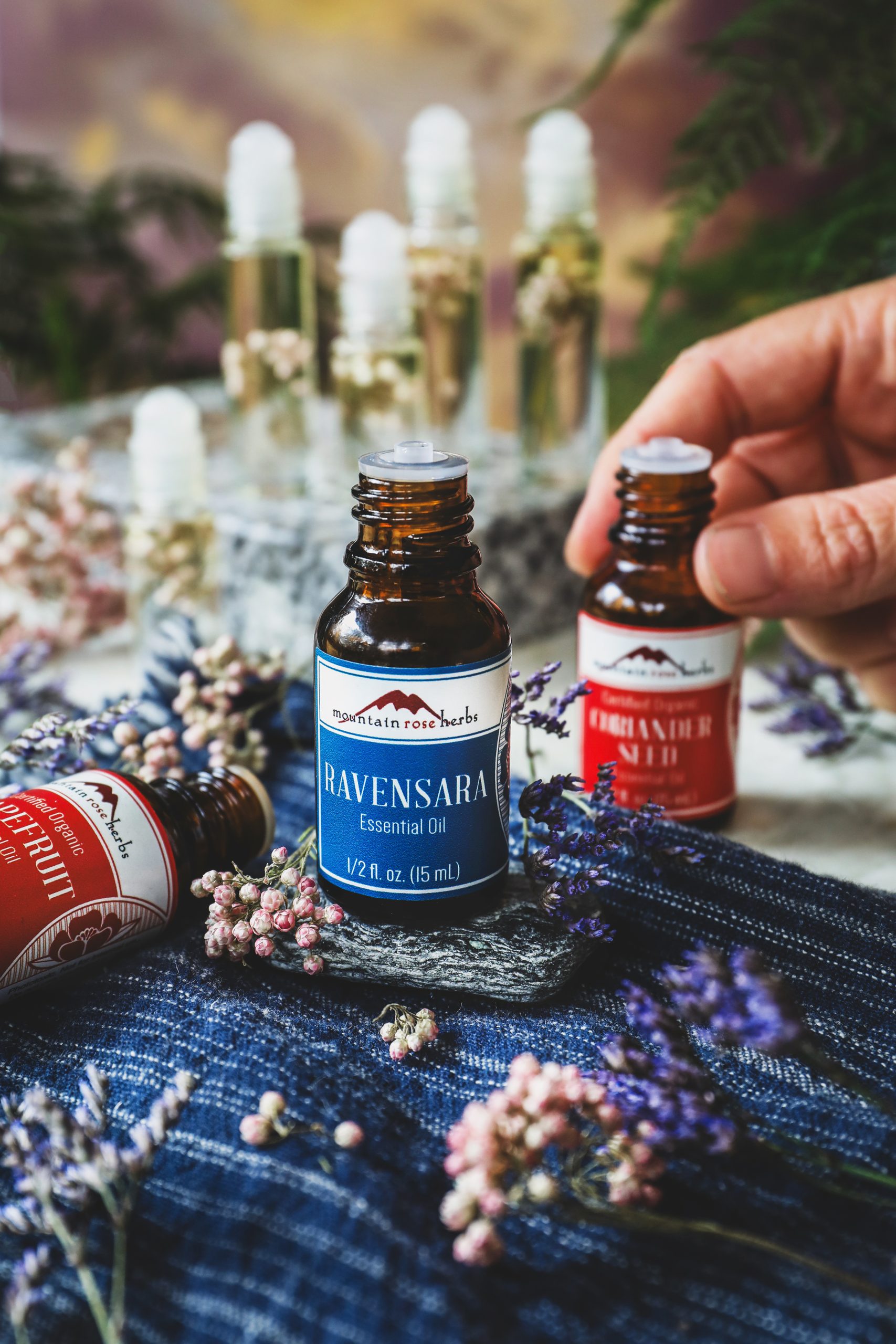 Essential oils used for wind perfume sit out surrounded by small pink flowers. 