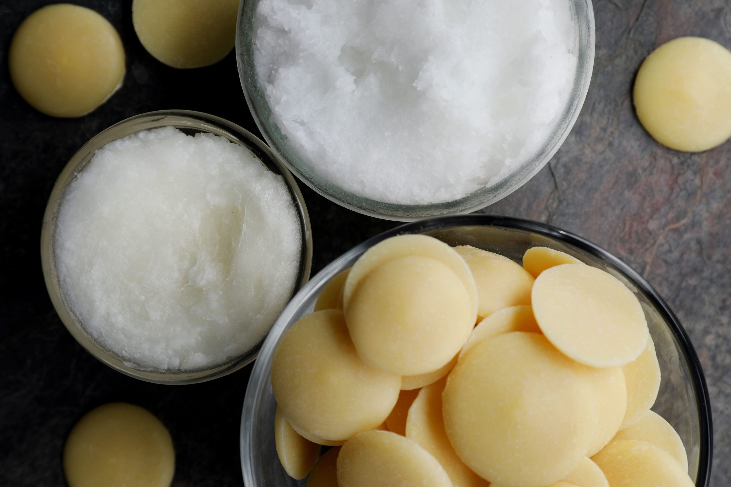 Three glass bowls will with butters and butter wafers on a rustic slab of slate. 