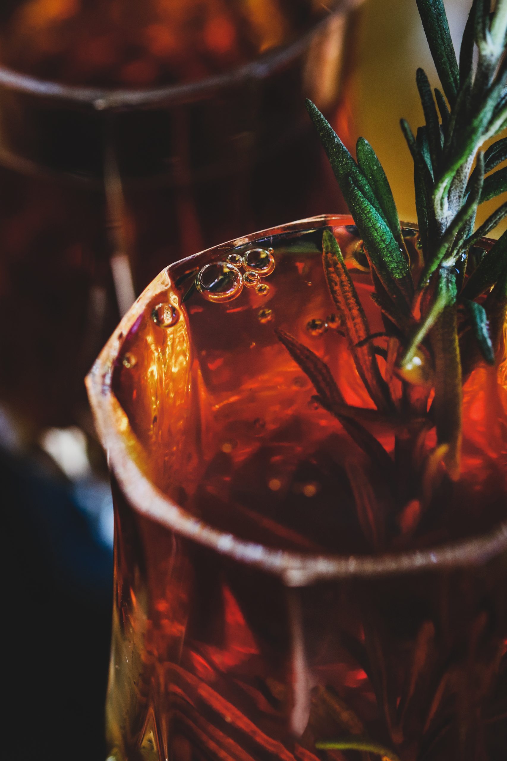 Looking into a glass of homemade cordial with a floating rosemary stem