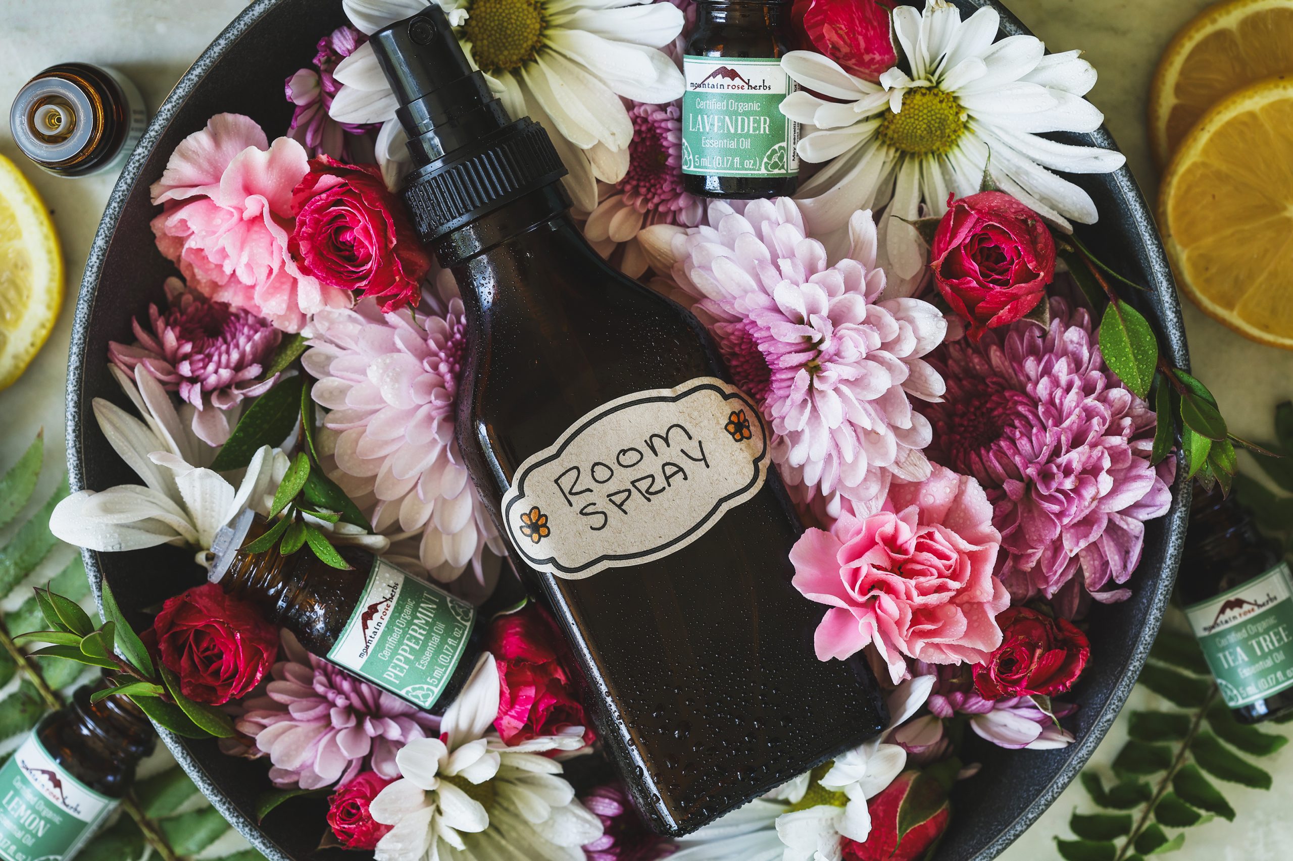 An overhead photo of a room spray bottle surrounded with flowers 