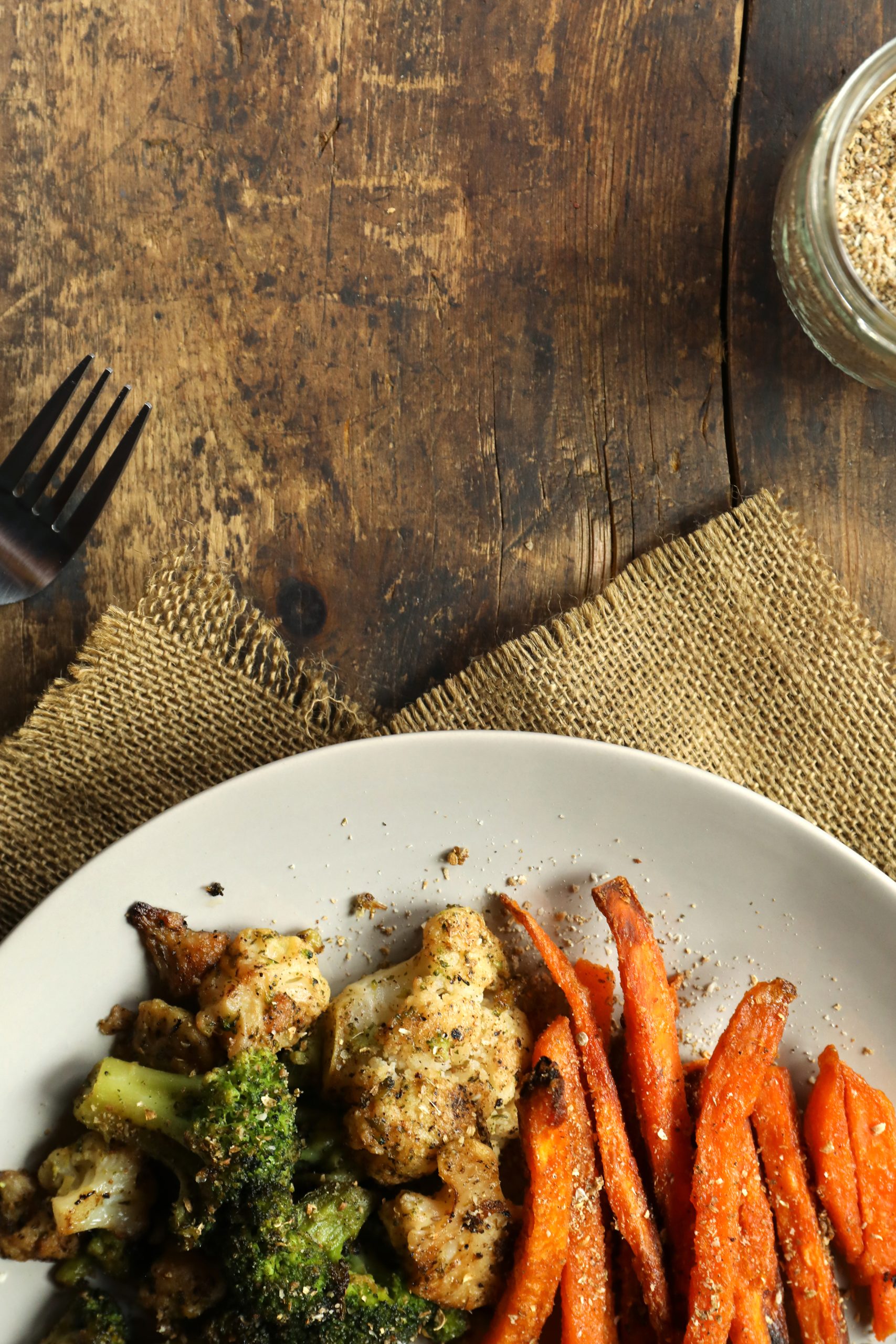 Dukkah seasoned grilled veggies on white plate on rustic table.