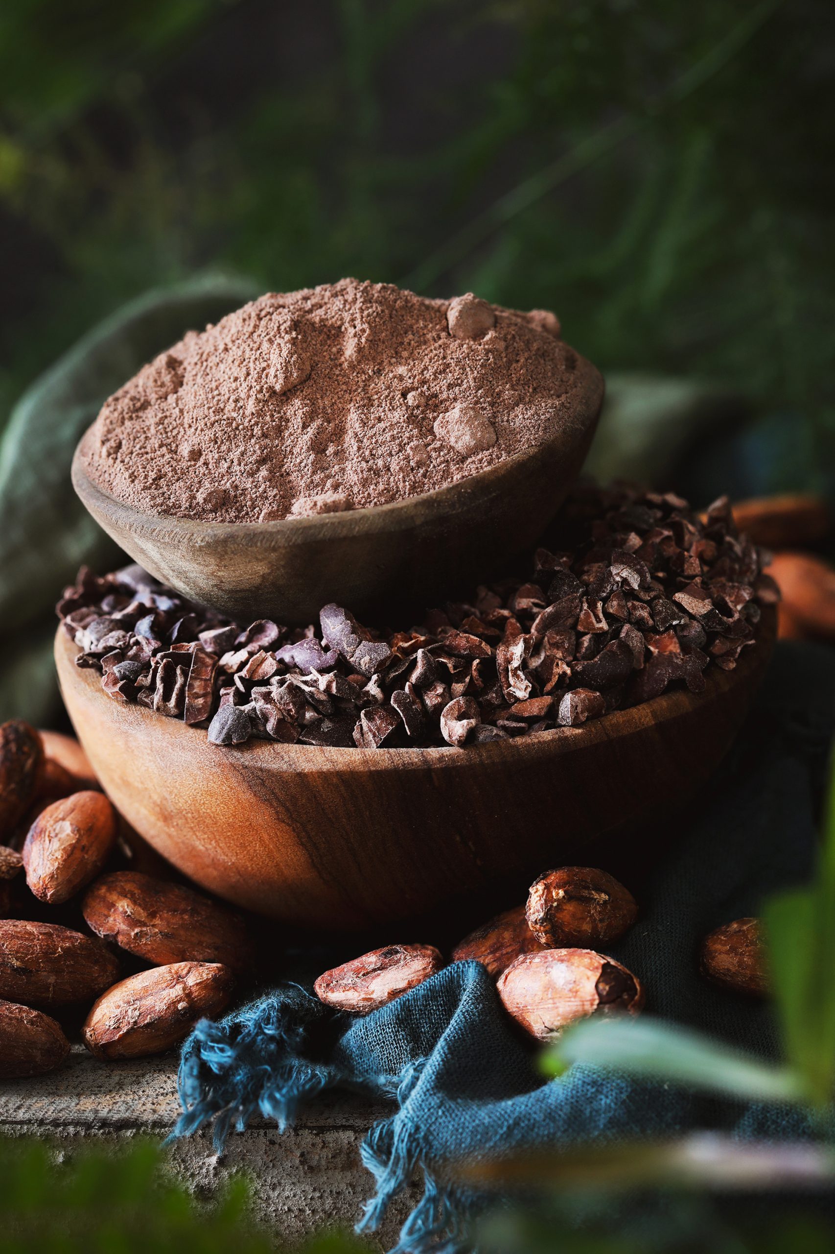 A selection of fair trade cacao powder, cacao nibs, and cacao beans in bowls