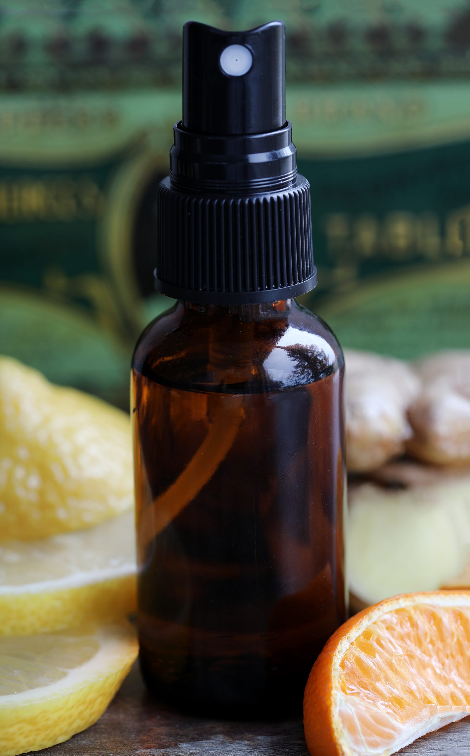 Amber glass bottle with a mister top surrounded by fresh citrus and ginger.