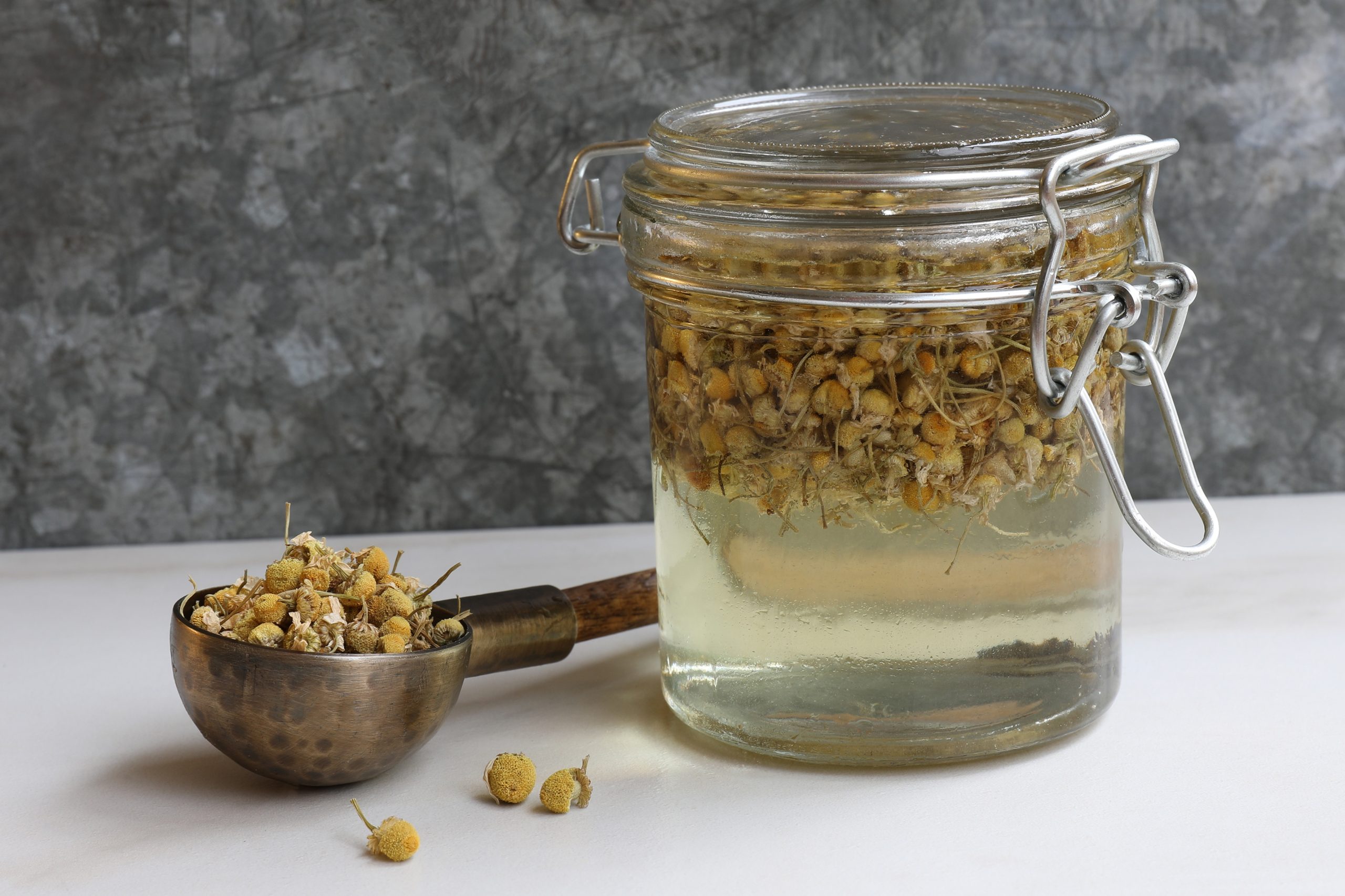 Pantry jar filled with vegetable glycerine and chamomile flowers to make an extraction