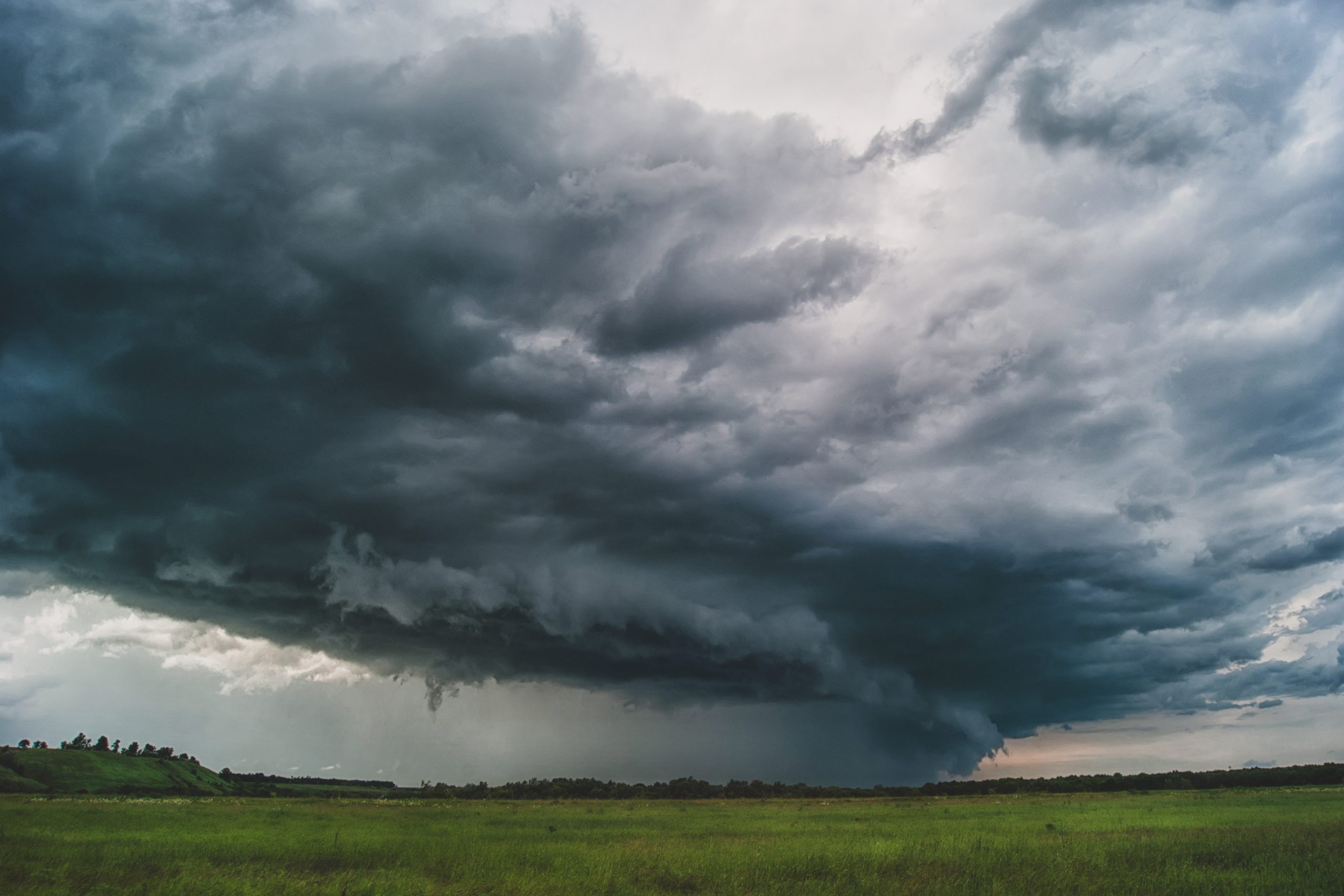 A dark and stormy sky gathers over a green field