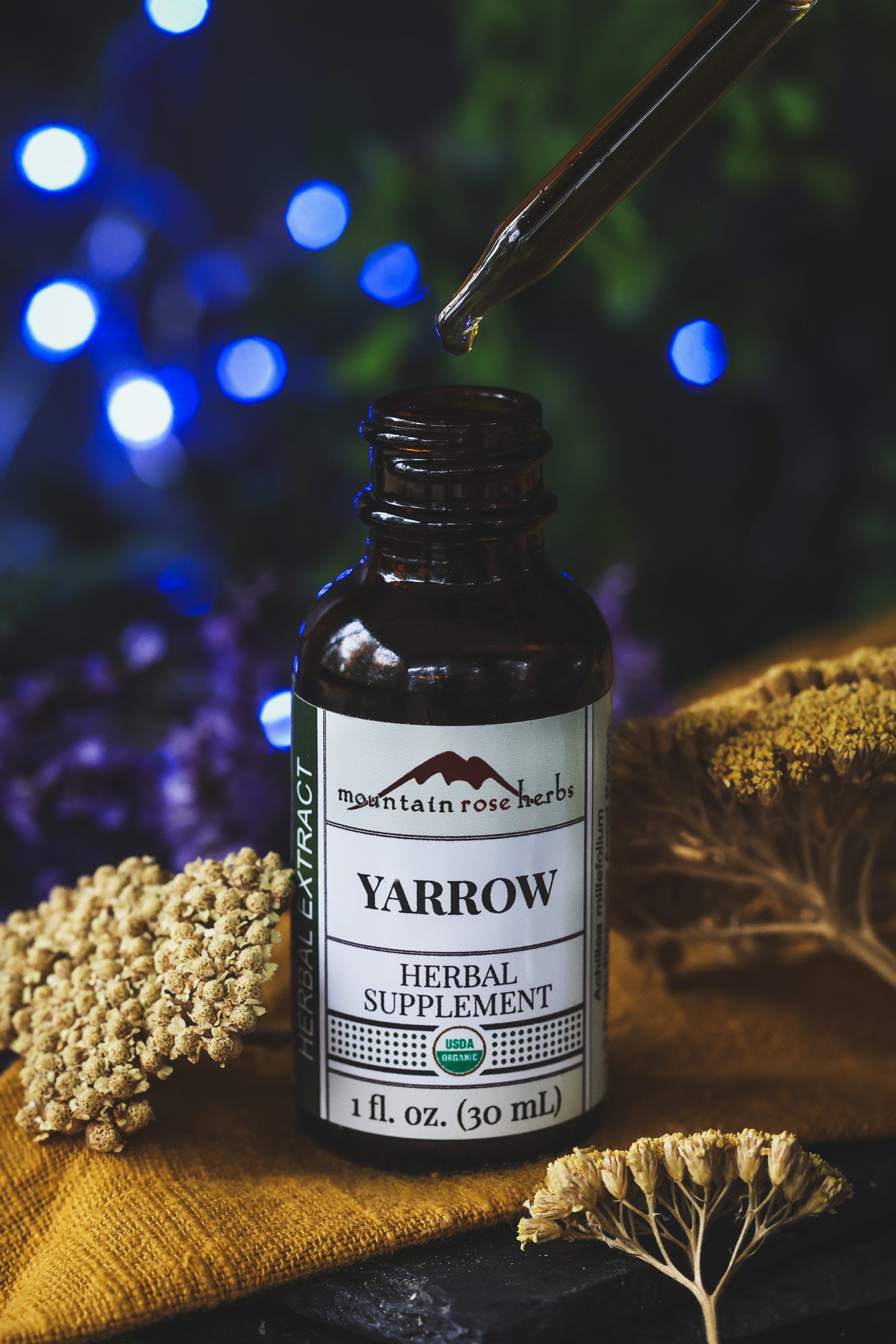 A bottle of yarrow extract with dried yarrow flowers around it