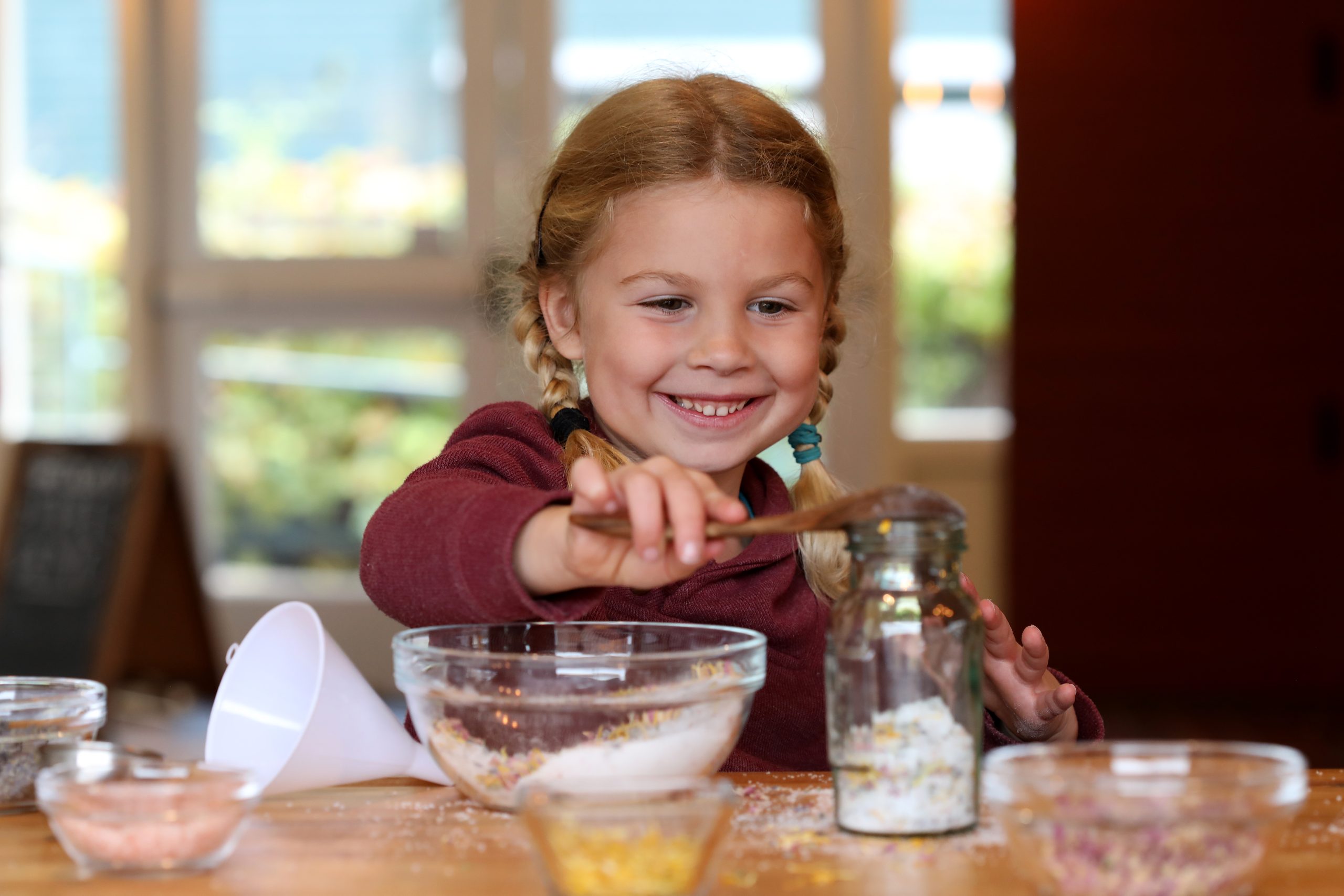 Child scooping salts in a jar