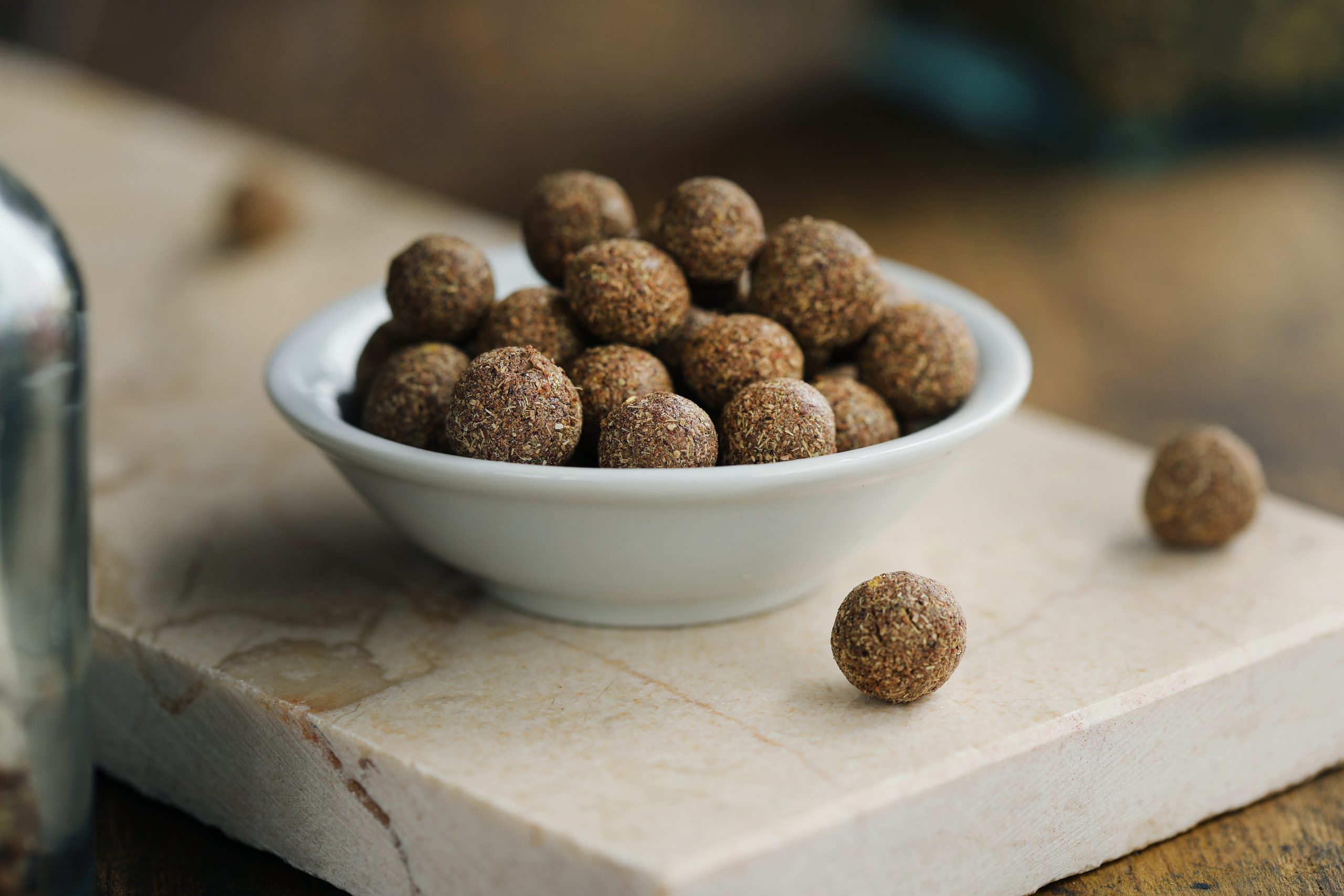 Small white bowl of brown speckled homemade herbal lozenges in home apothecary.