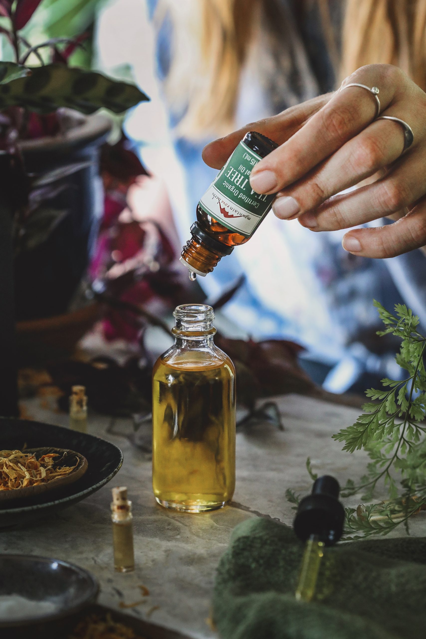 Essential oil dripping into a bottle of carrier oil.