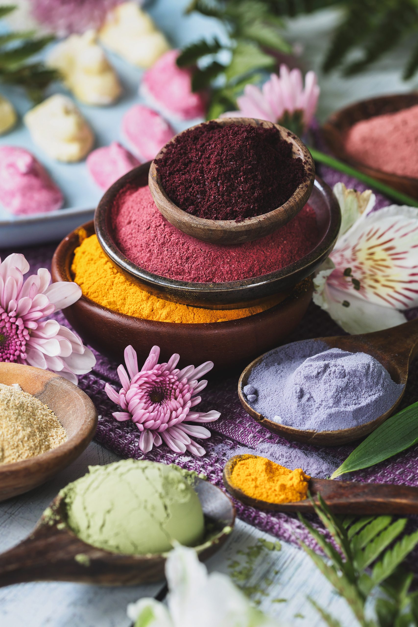 A stack of colorful herbal powders in bowls with marshmallows in the background