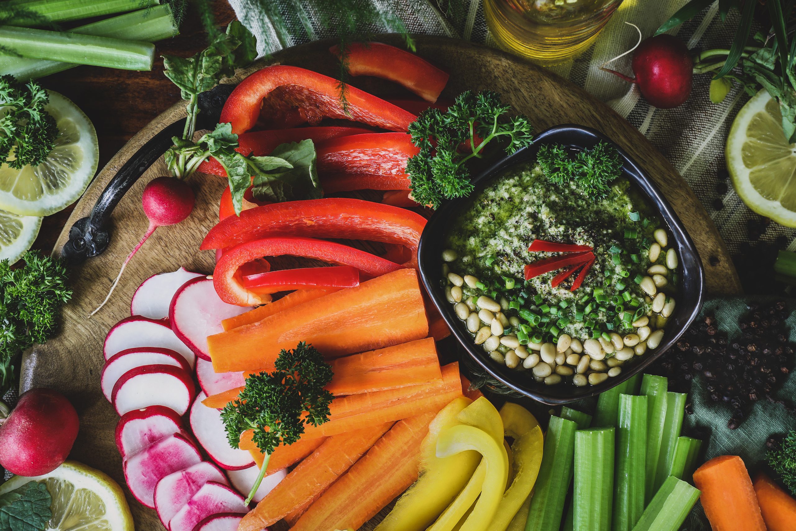 A bowl of pesto sits out with a veggie spread