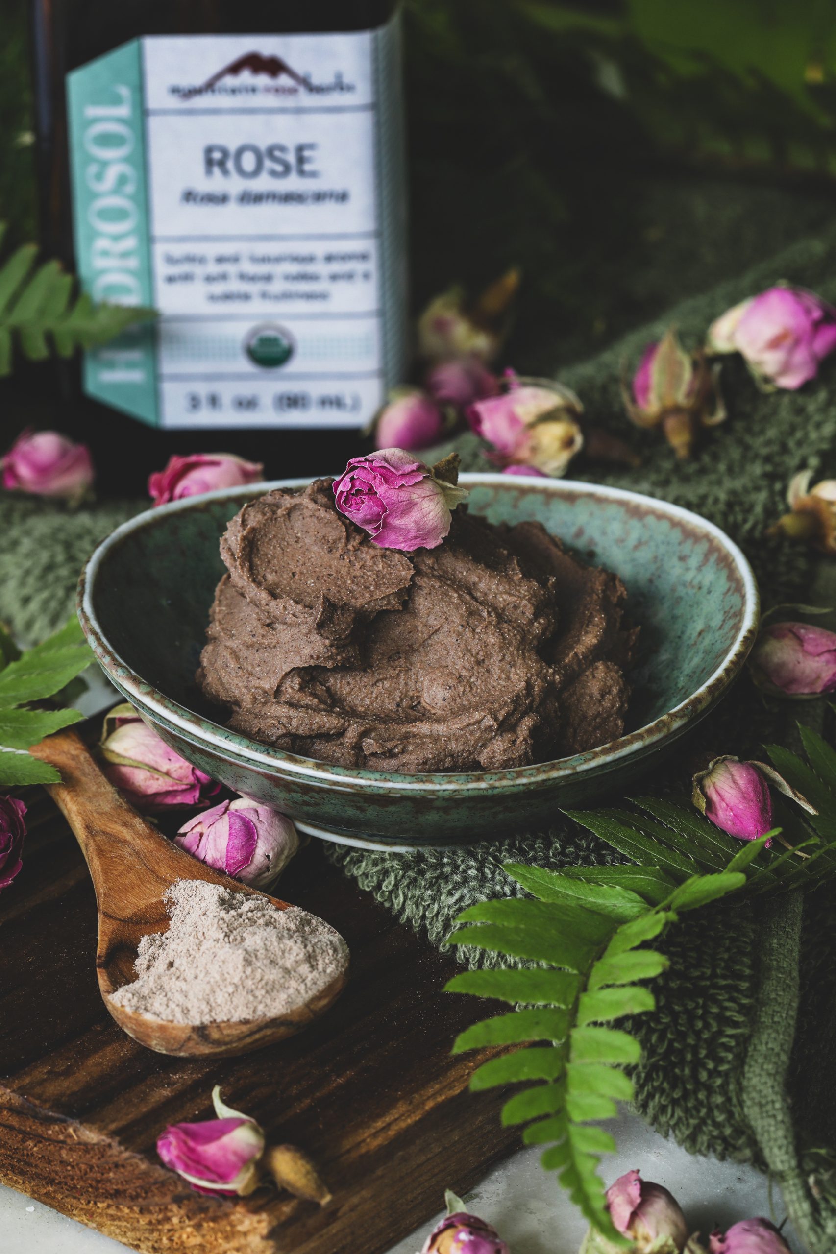 A bowl of rhassoul clay sits beside rose hydrosol