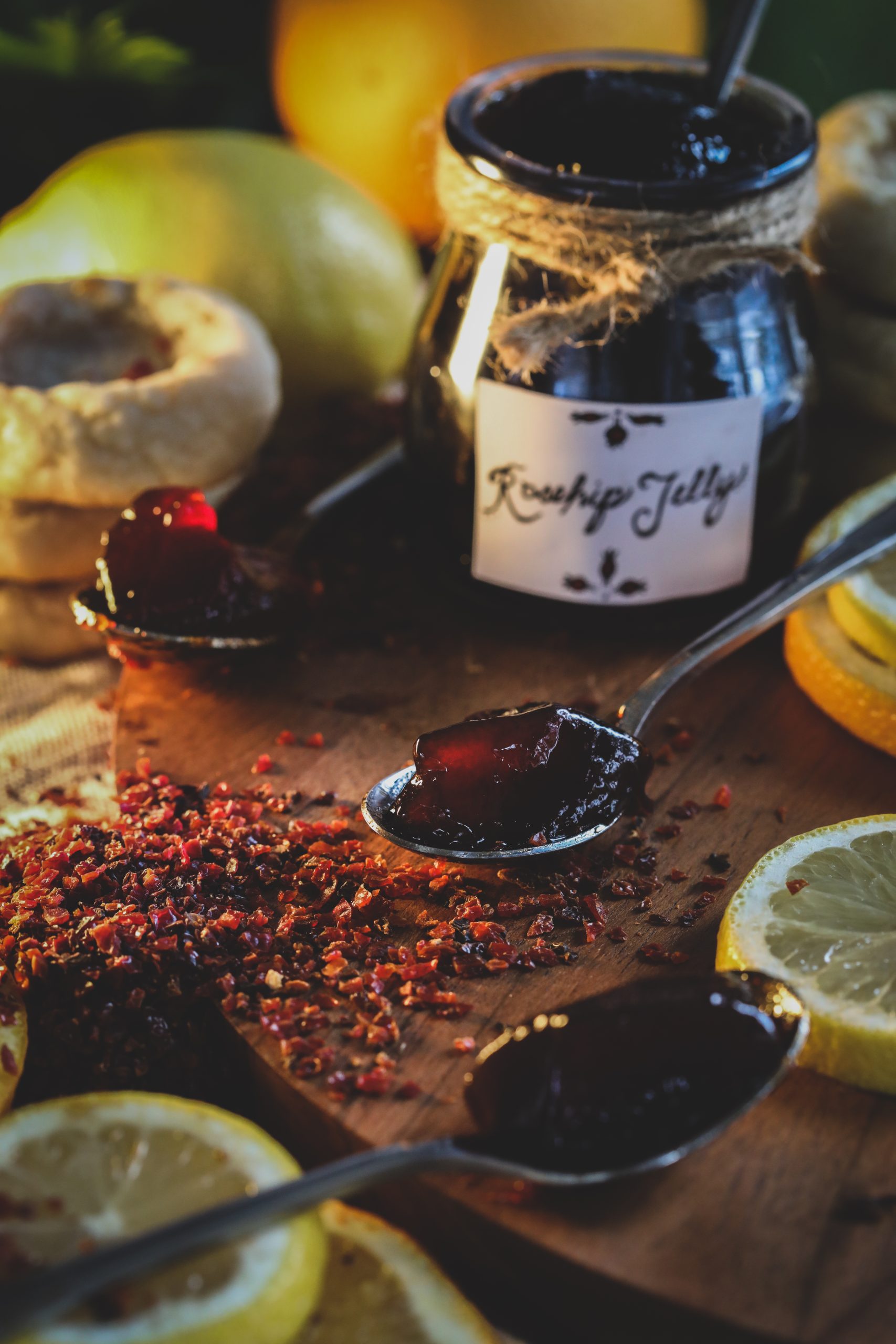 Rosehip Jelly on spoons surrounded by  dried rosehips and fresh lemon slices 