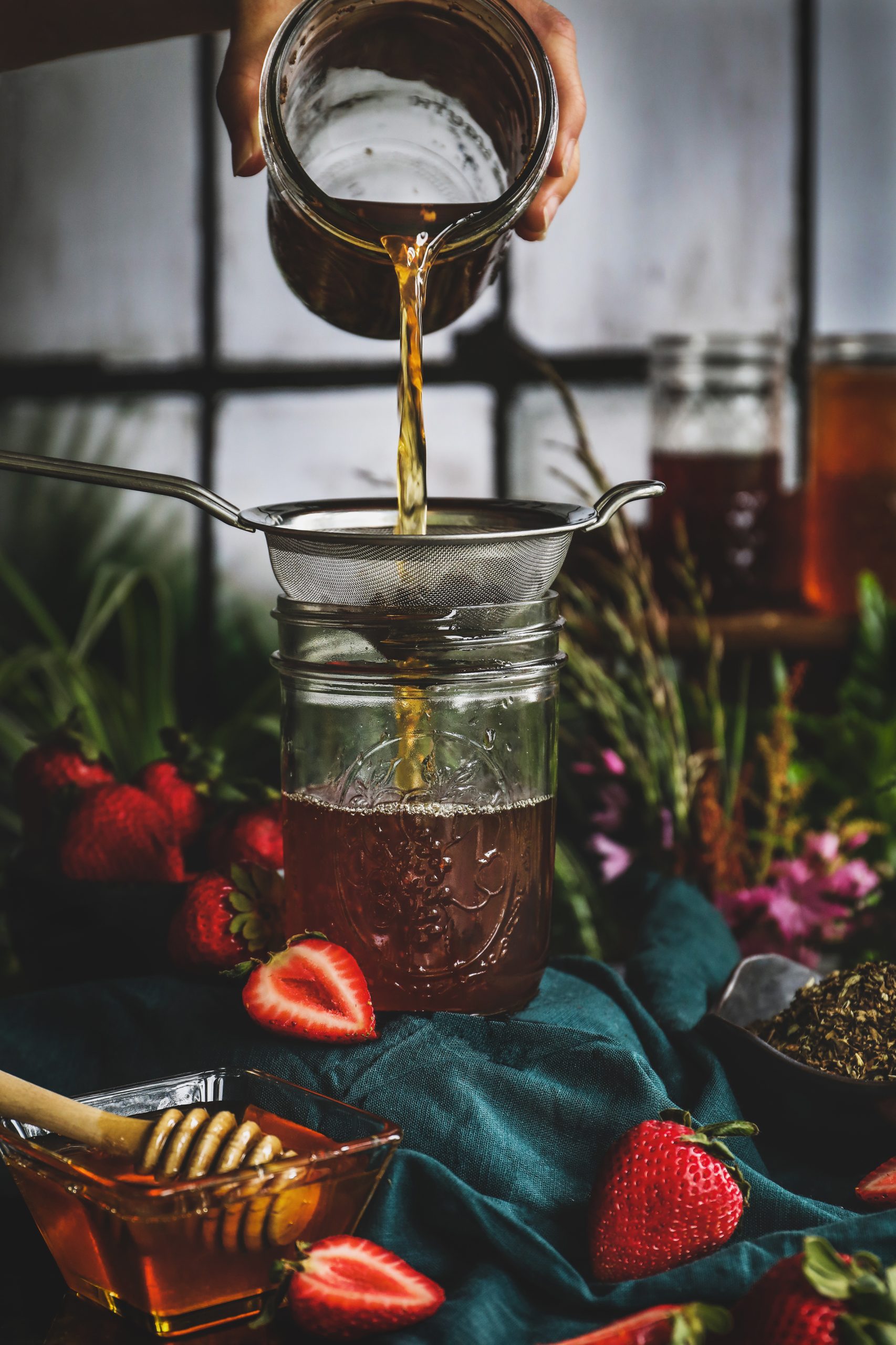 Someone straining a holy basil drinking vinegar.