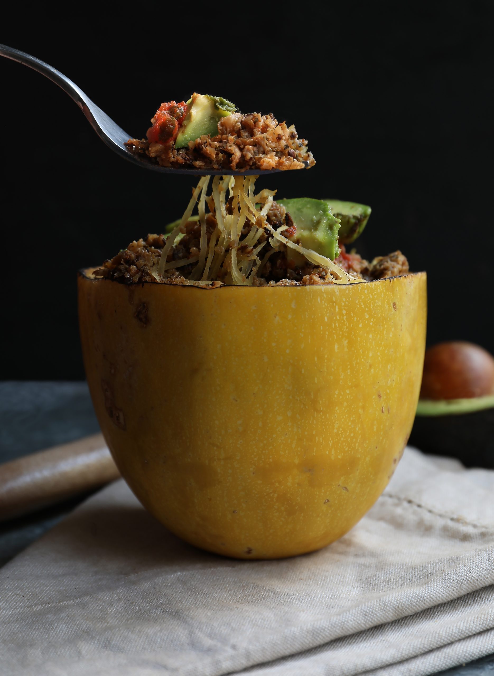 Fork lifting spaghetti squash noodles out of spaghetti squash bowl