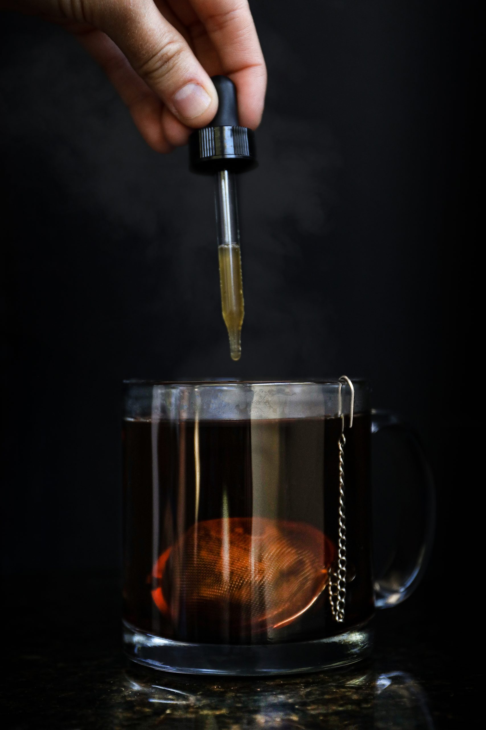 Herbal elixir for stress relief made from Krishna holy basil, aswagandha root, astragalus root, and honey being dripped into a cup of tea.