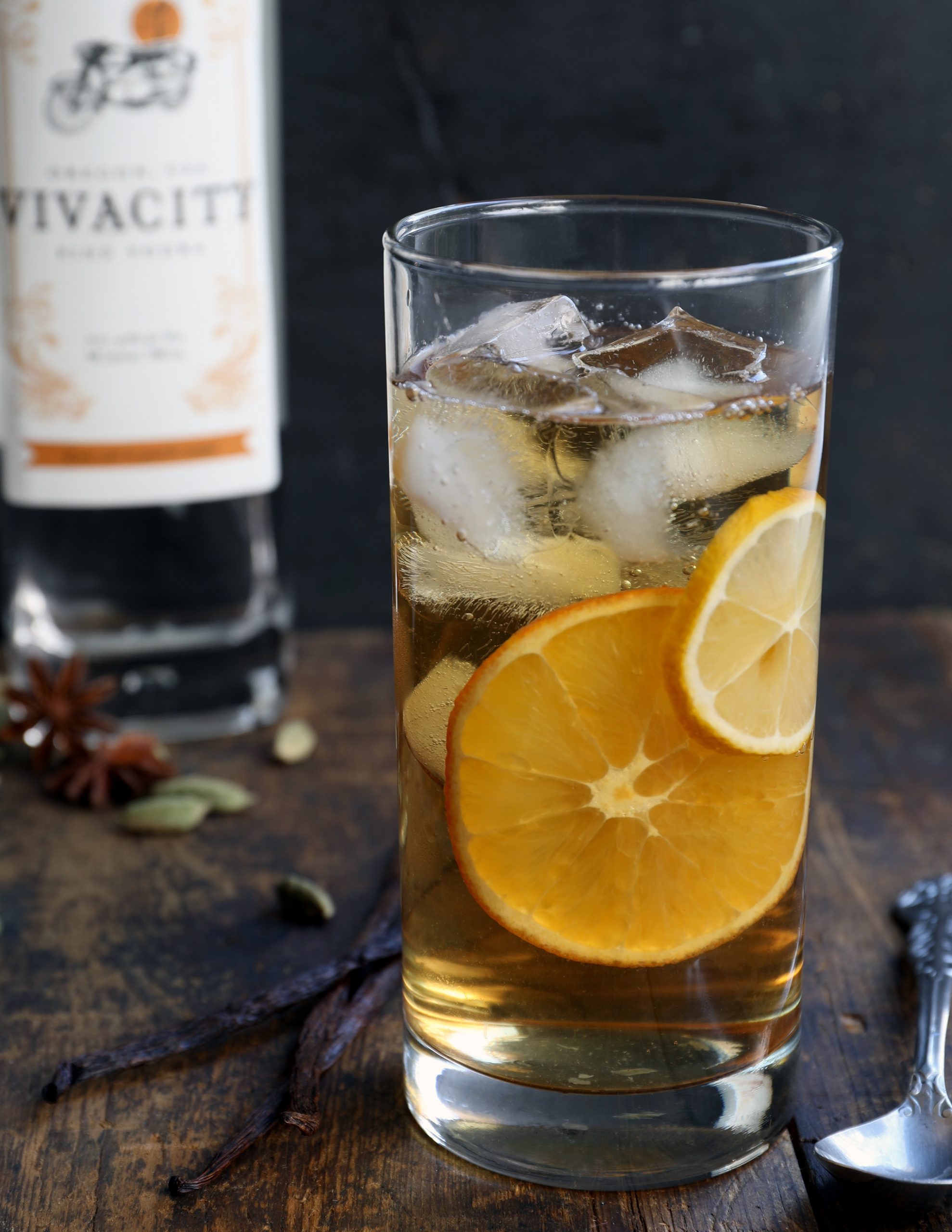 Tall glass with iced vermouth drink with lemon in it sitting on wooden table Tall glass with iced vermouth drink with lemon in it sitting on wooden table