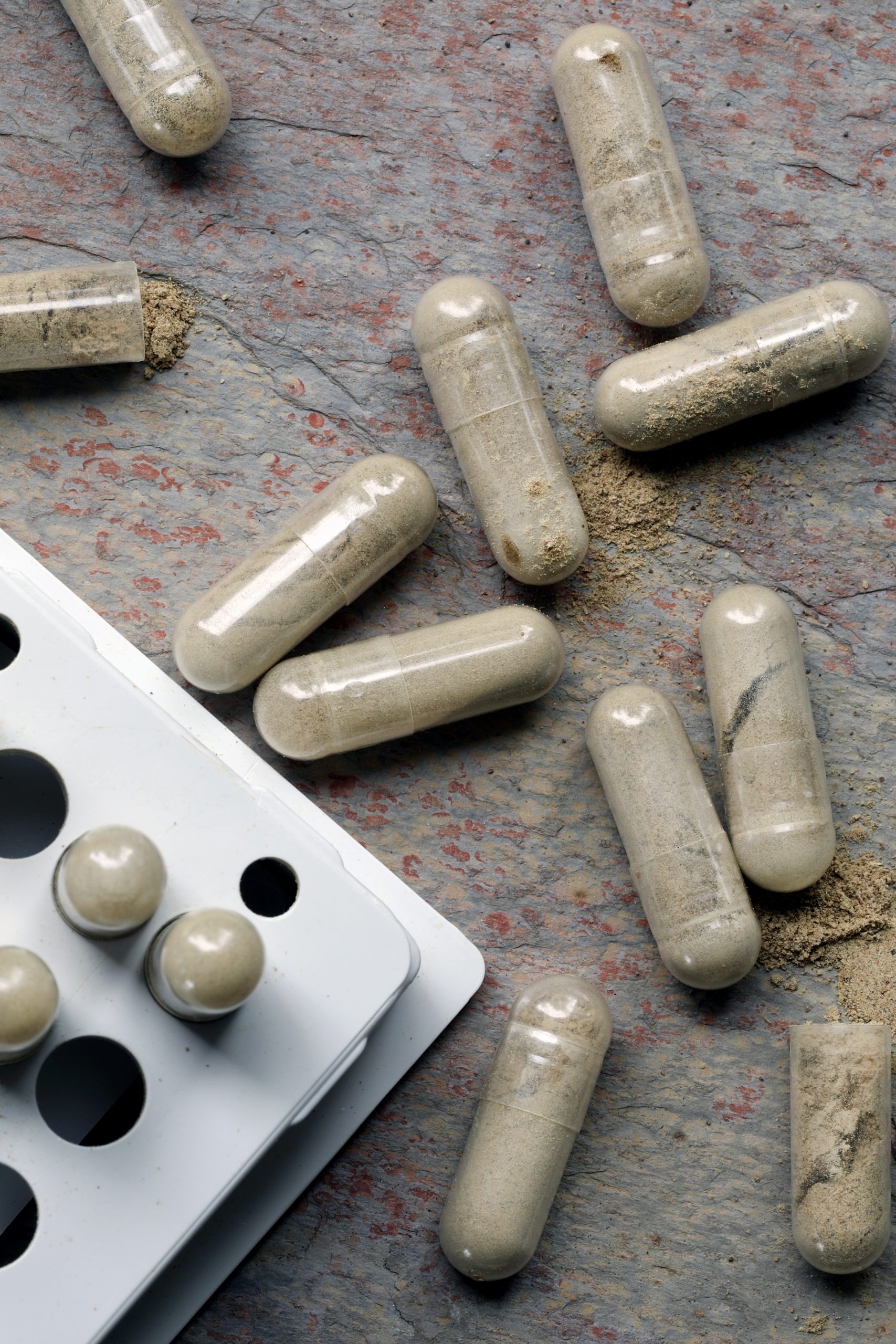 Capsules filled with triphala powder laying out on granite counter
