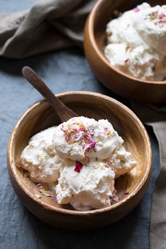 Wooden bowl filled with vanilla rose ice cream sprinkled with rose petals  with wooden spoon