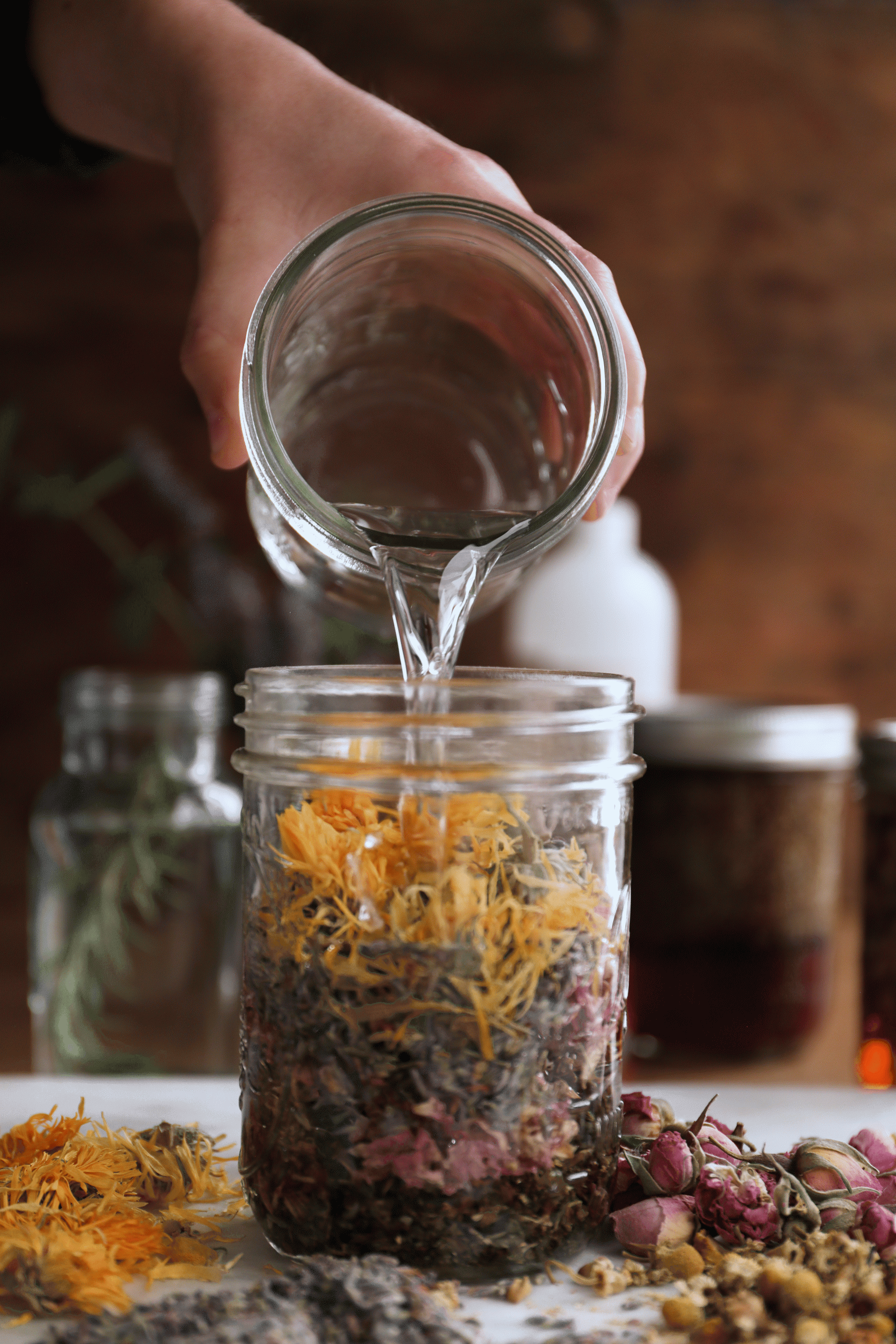 GIF of witch hazel being poured over herbs in a jar.