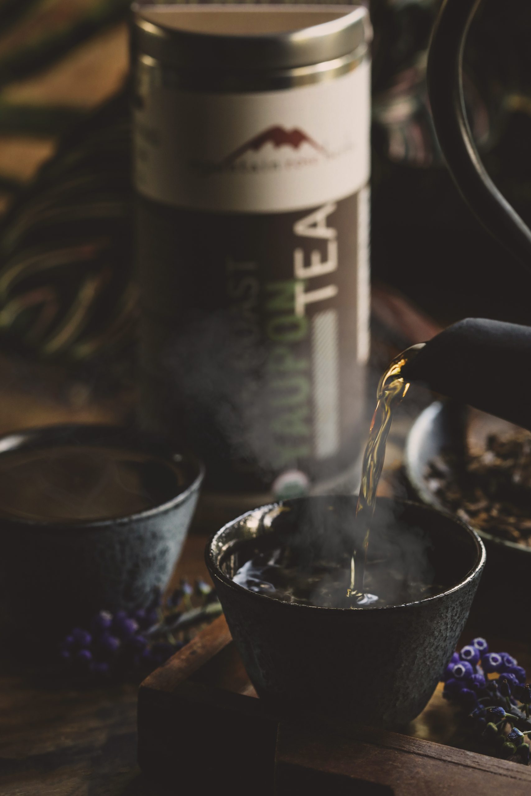 Hot yaupon tea being poured into a cup with steam rising.