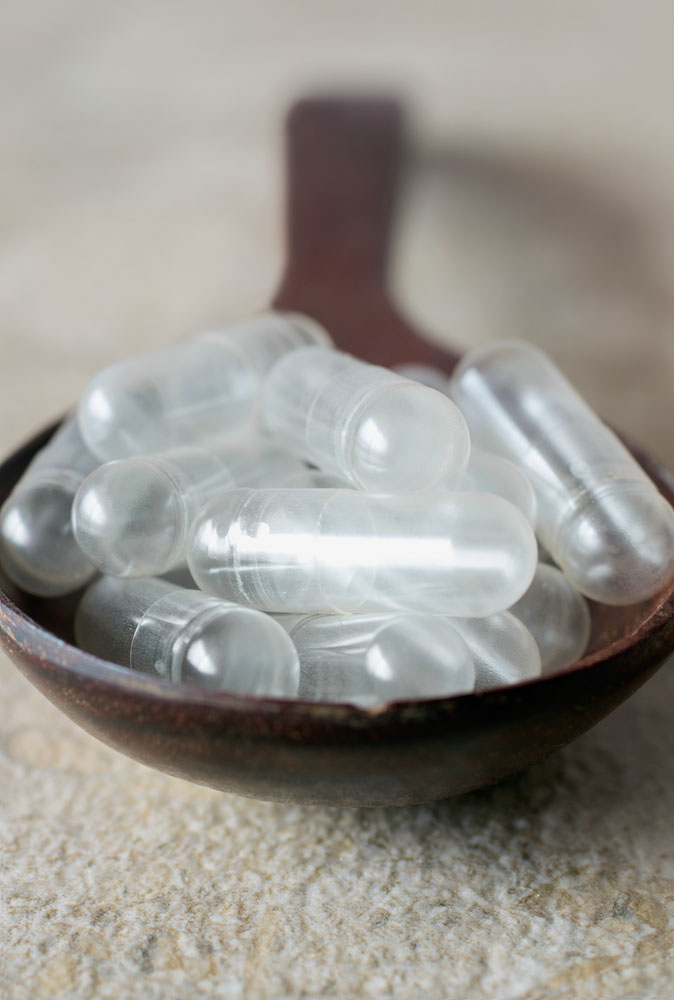 A wooden spoon full of empty capsules 