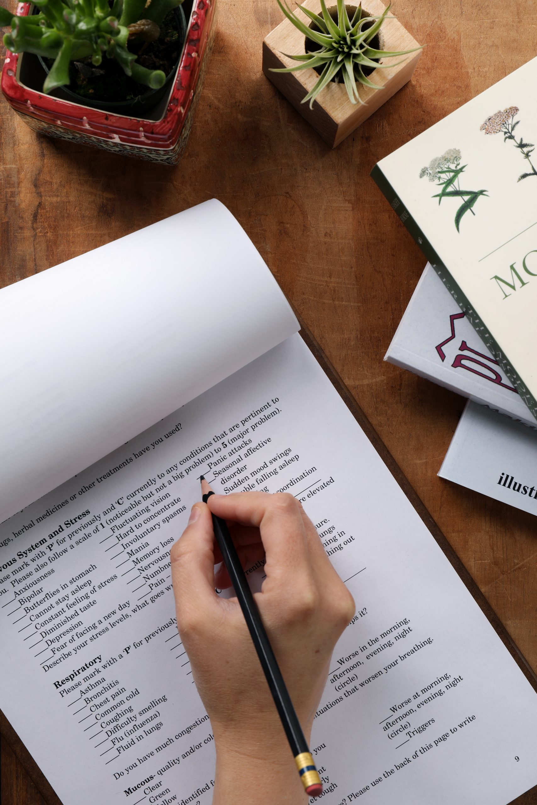 Filling out an intake form for a medical office surrounded by plants and herbalism books. 