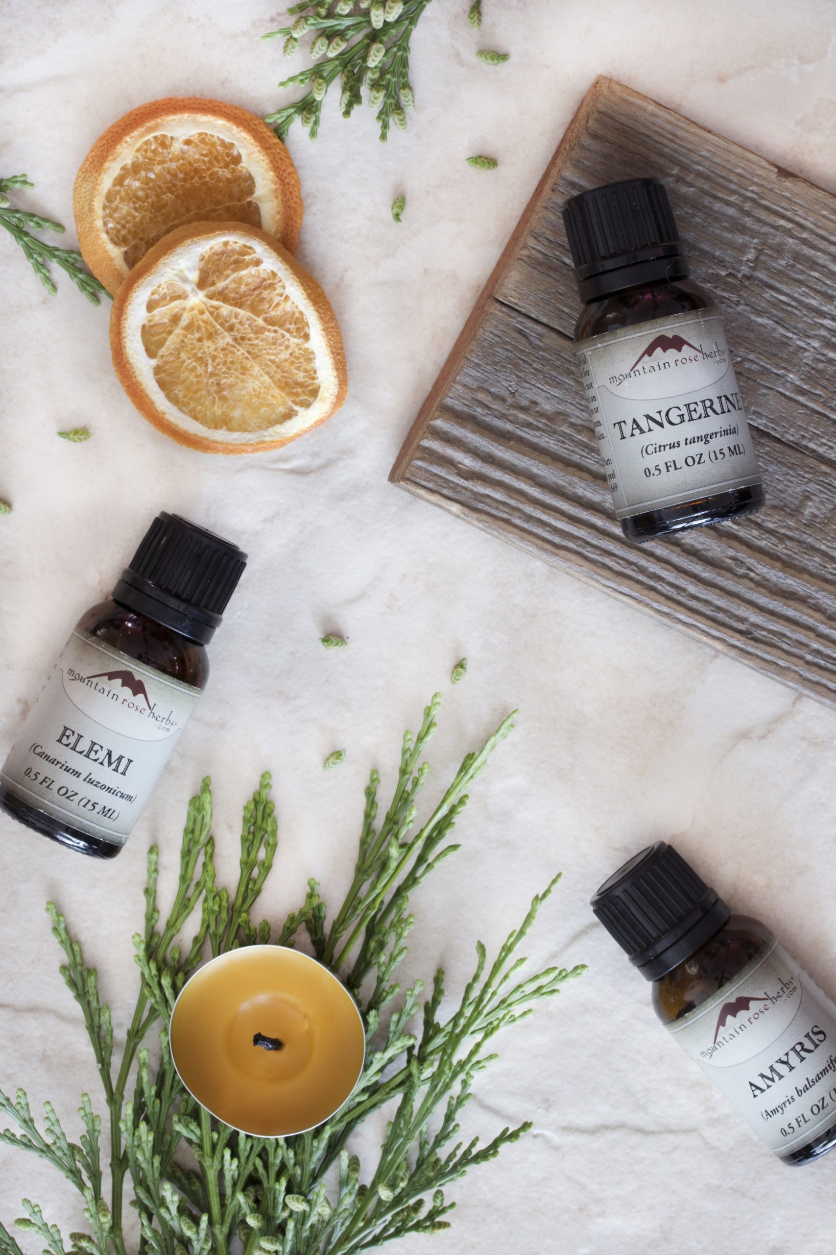 Variety of essential oils, elemi essential oil, tangerine essential oil, and amyris essential oil laying out on counter
