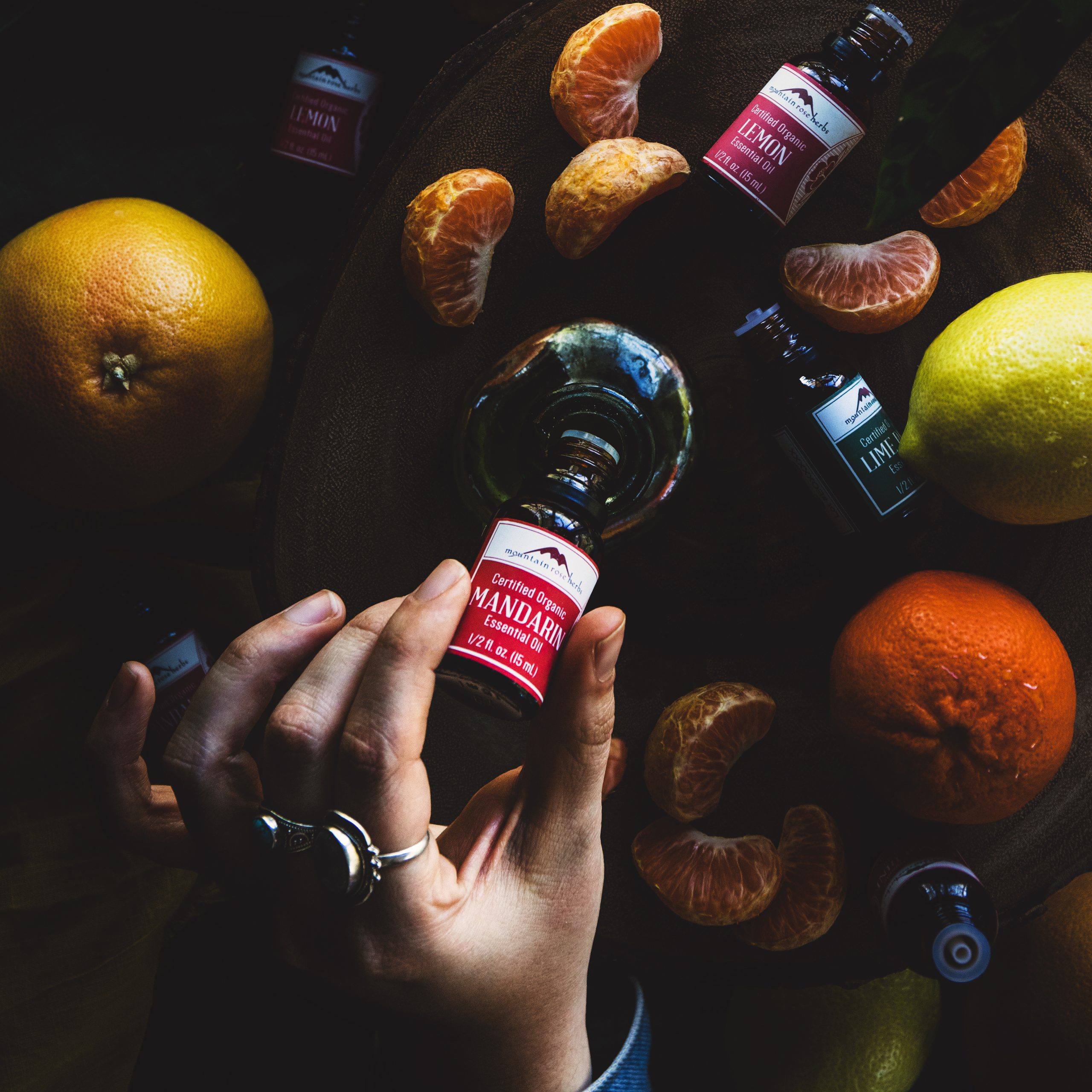 A bottle of mandarin essential oil gets poured into a vessel