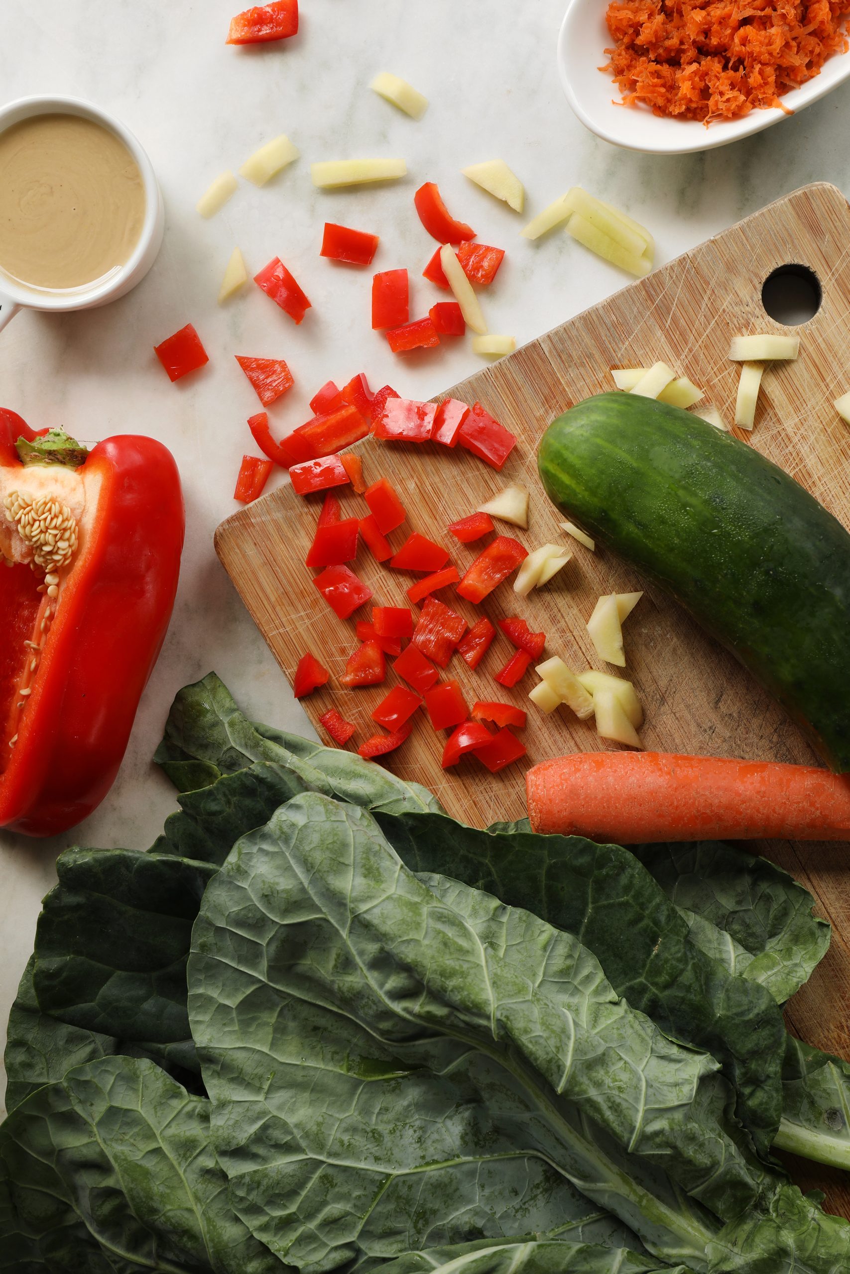 Organic vegetables prepared to come together in a collard green wrap with vegan falafel and tahini sauce. Organic carrots, red bell pepper, cucumber, and collard greens chopped, shredded, and diced.
