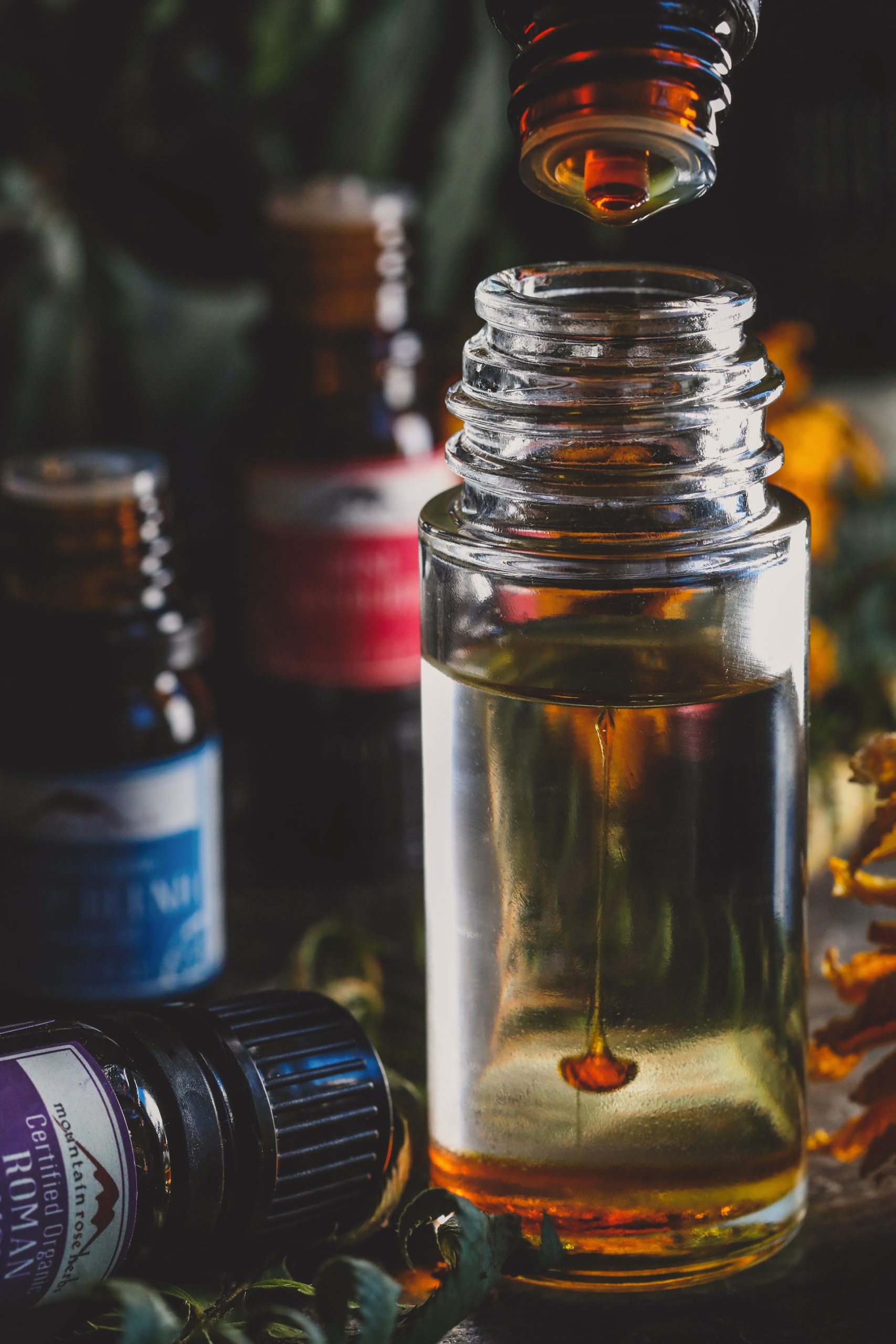 Amber colored essential oil dropping into clean class bottle. 