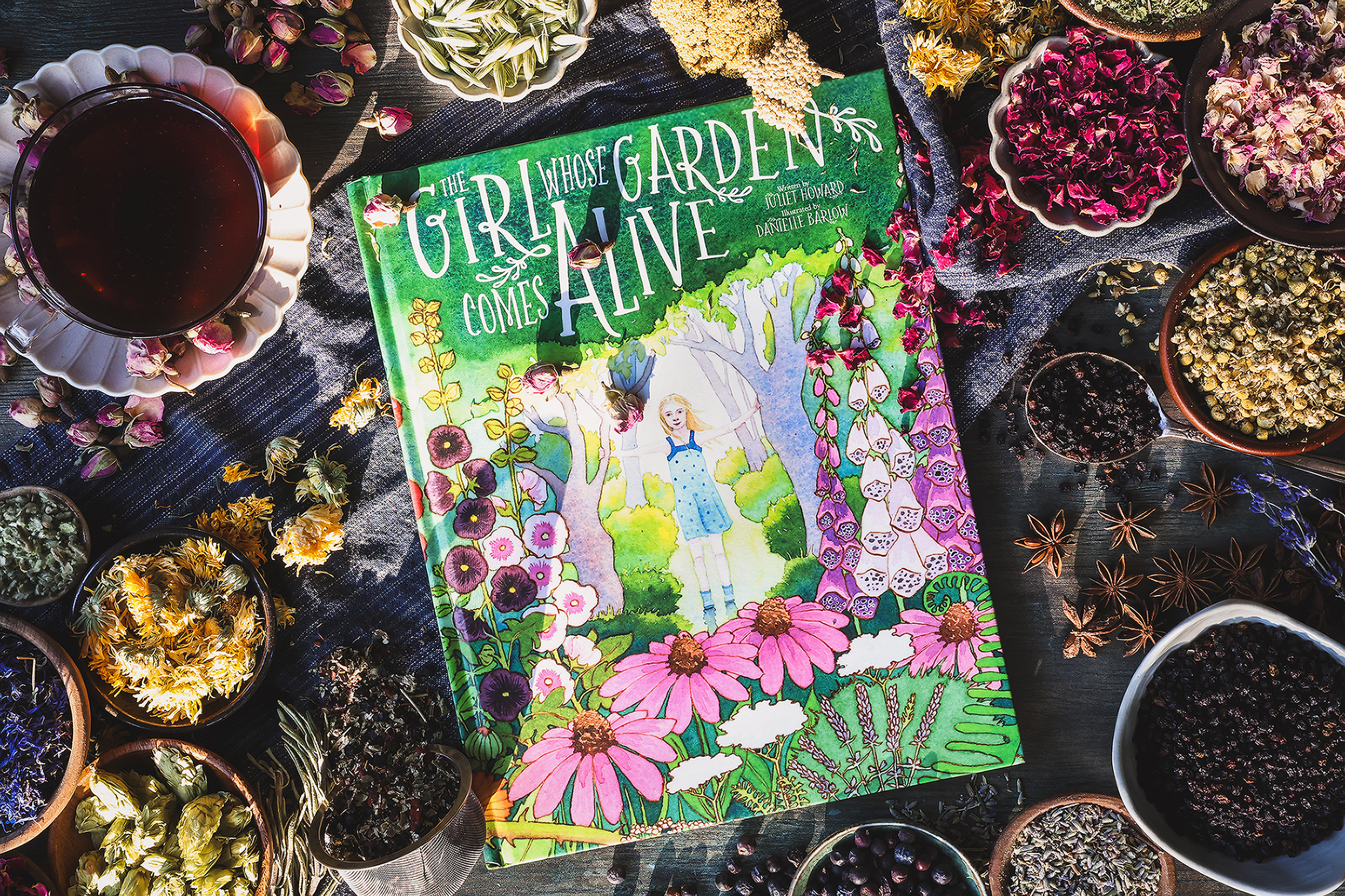 An overhead photo of a children's activity book with tea and dried herbs around it