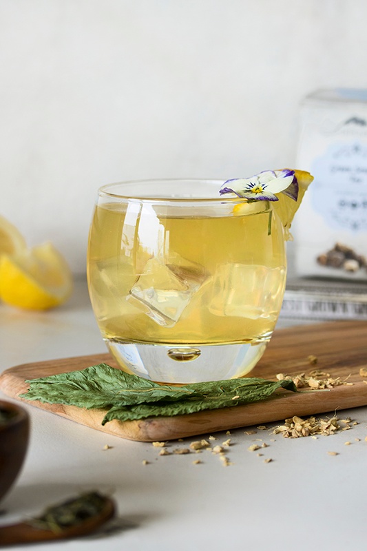 Clear glass of ginger palmer mocktail with ice cubes with lemon wedges and ginseng Clear glass of ginger palmer mocktail with ice cubes with lemon wedges and ginseng