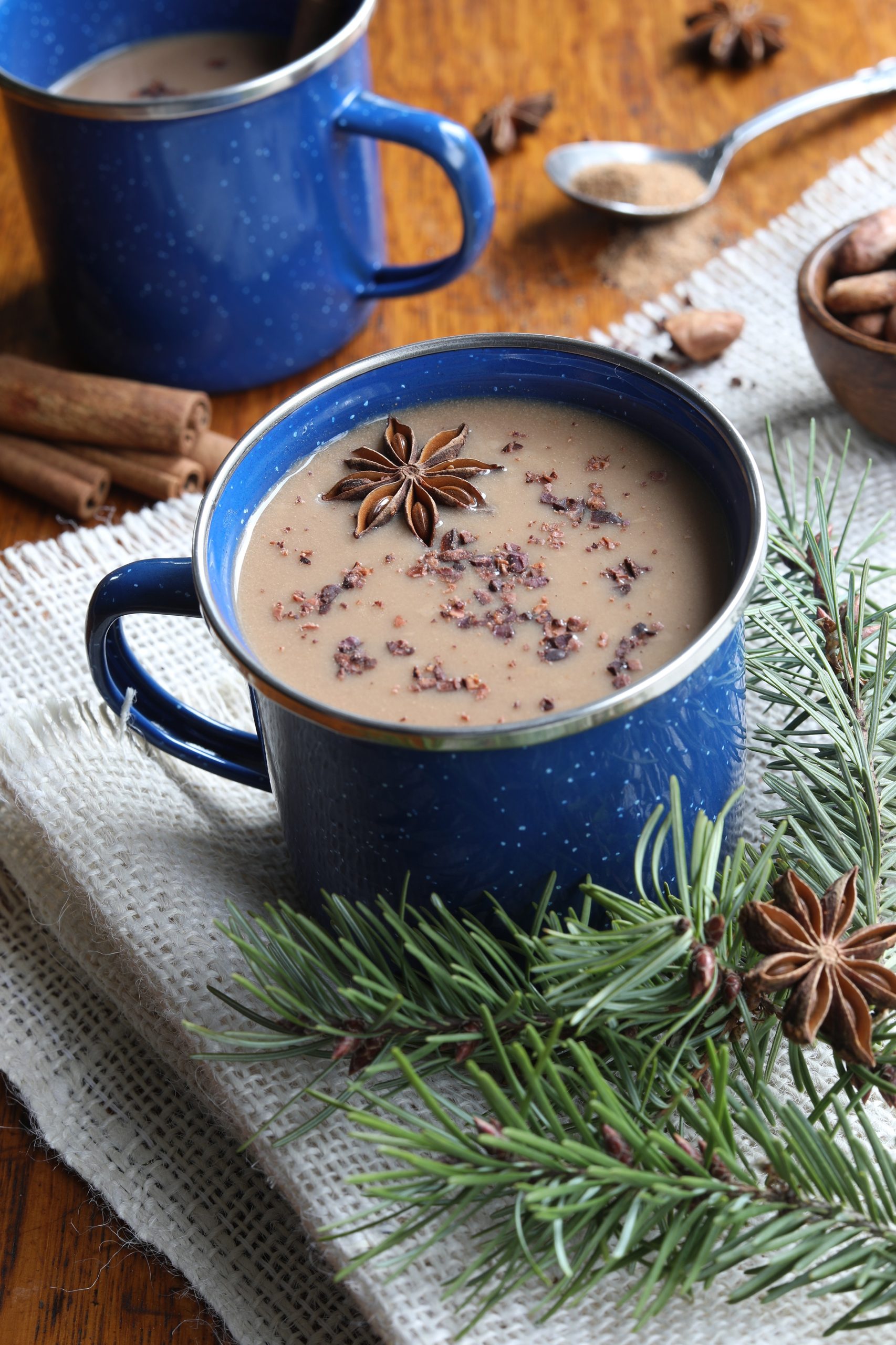 Camping mug with herbal hot chocolate sprinkled with herba and star anise, mug sitting on woven table cloth Camping mug with herbal hot chocolate sprinkled with herba and star anise, mug sitting on woven table cloth