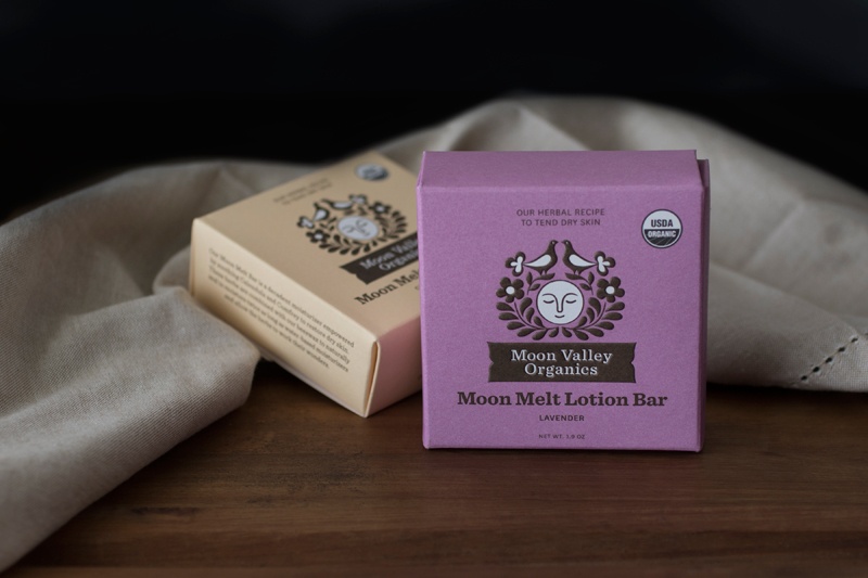 Moon Valley organic lotion bars in packaging on table with black background