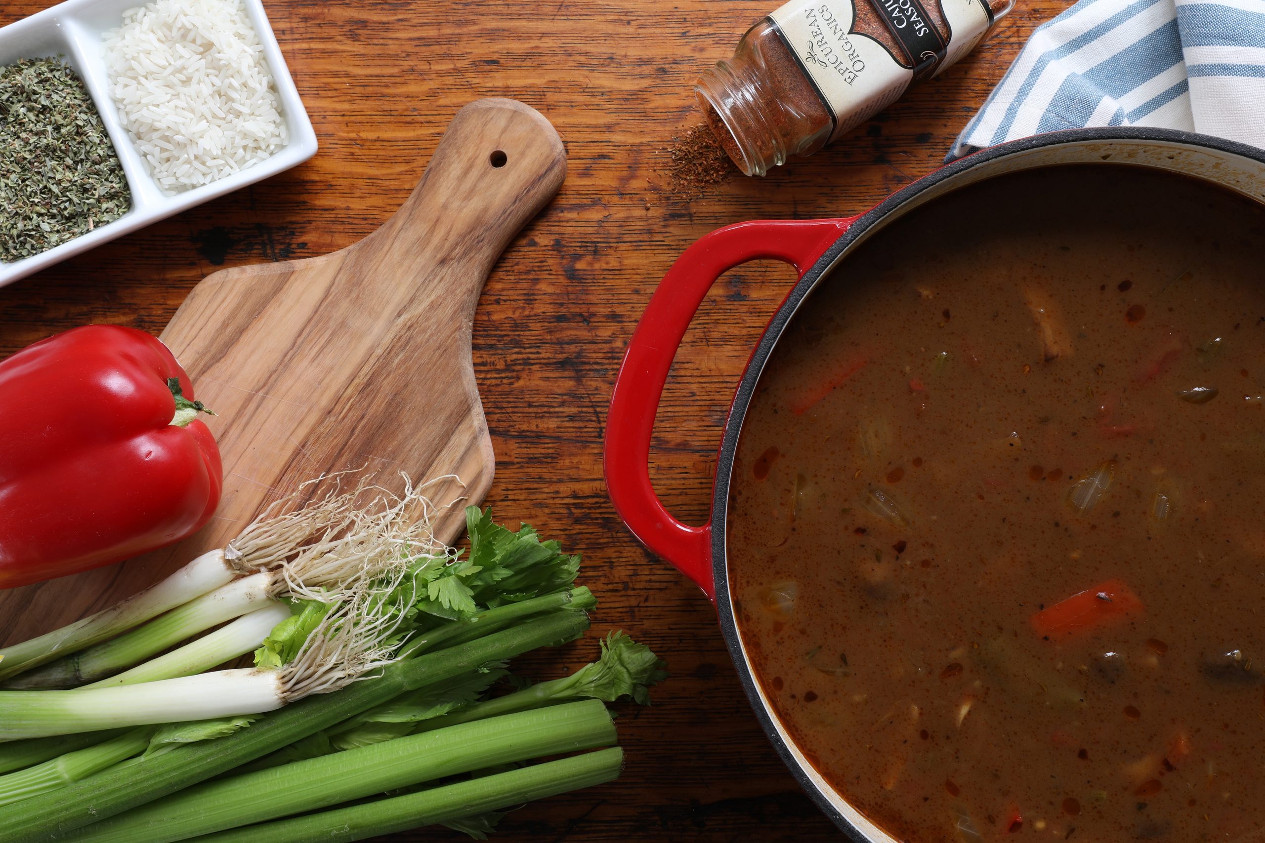 Vegetarian gumbo in pot with ingredients nearby on cutting board and spices and herbs nearby Vegetarian gumbo in pot with ingredients nearby on cutting board and spices and herbs nearby
