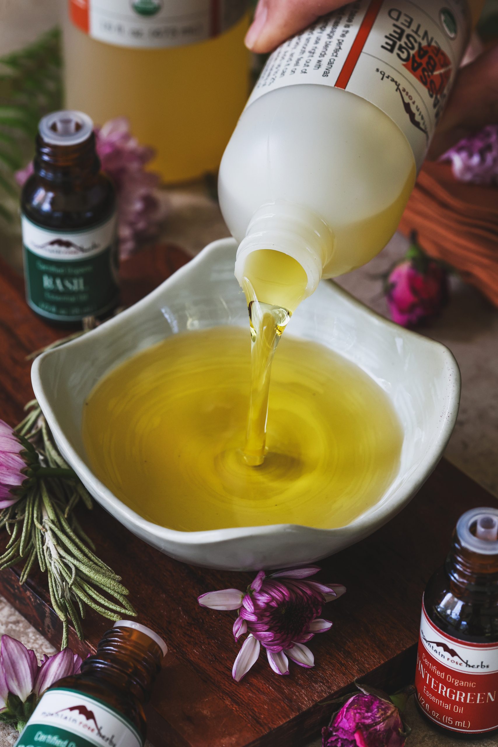 Massage oil base being poured into a bowl for essential oil blending