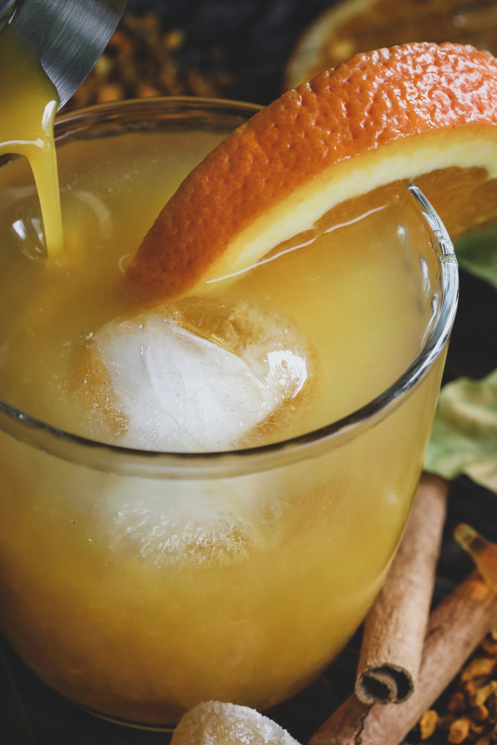 Ices orange cocktail being poured into glass.