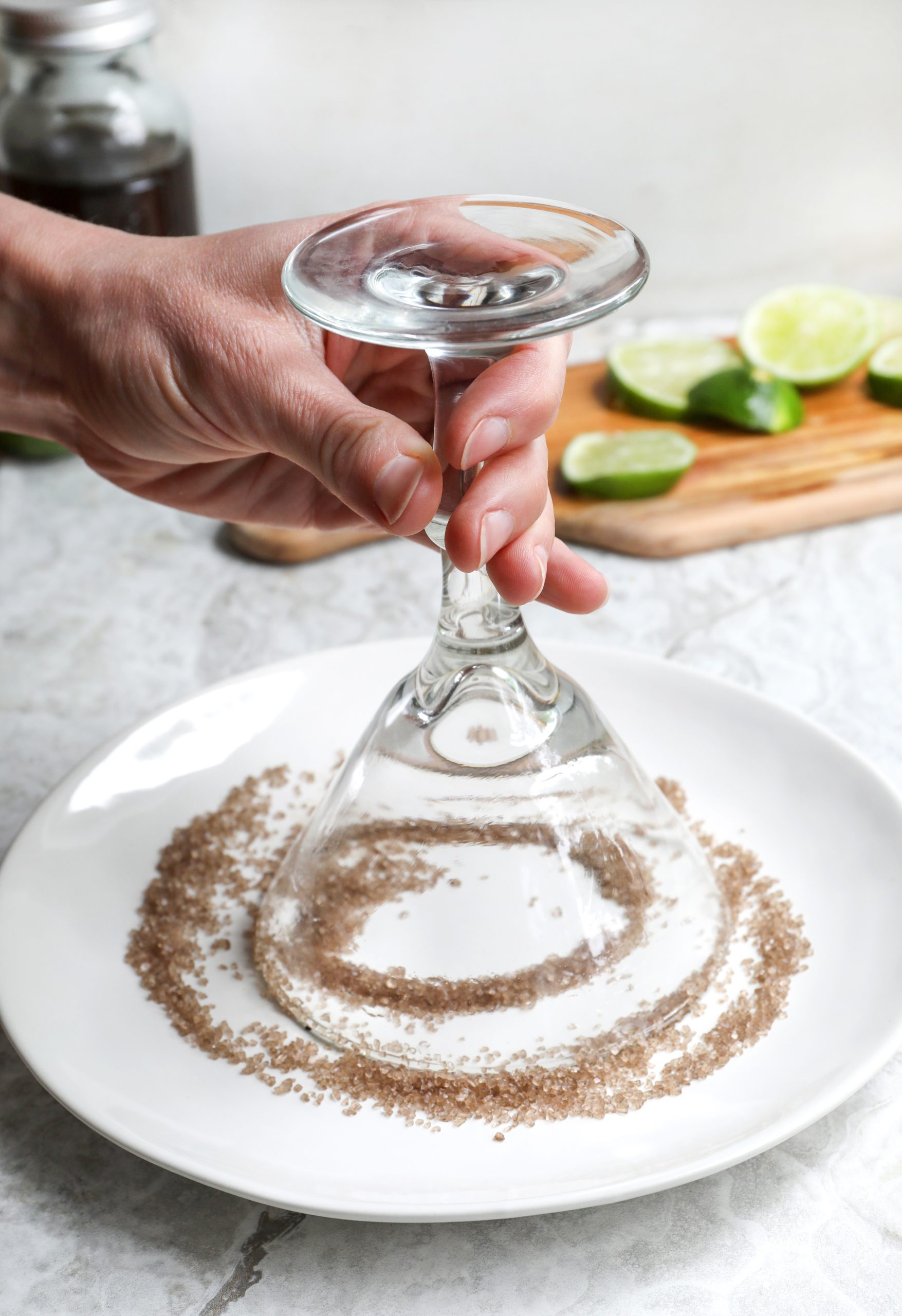 Hand holding margarita glass face down to cover rim with salt