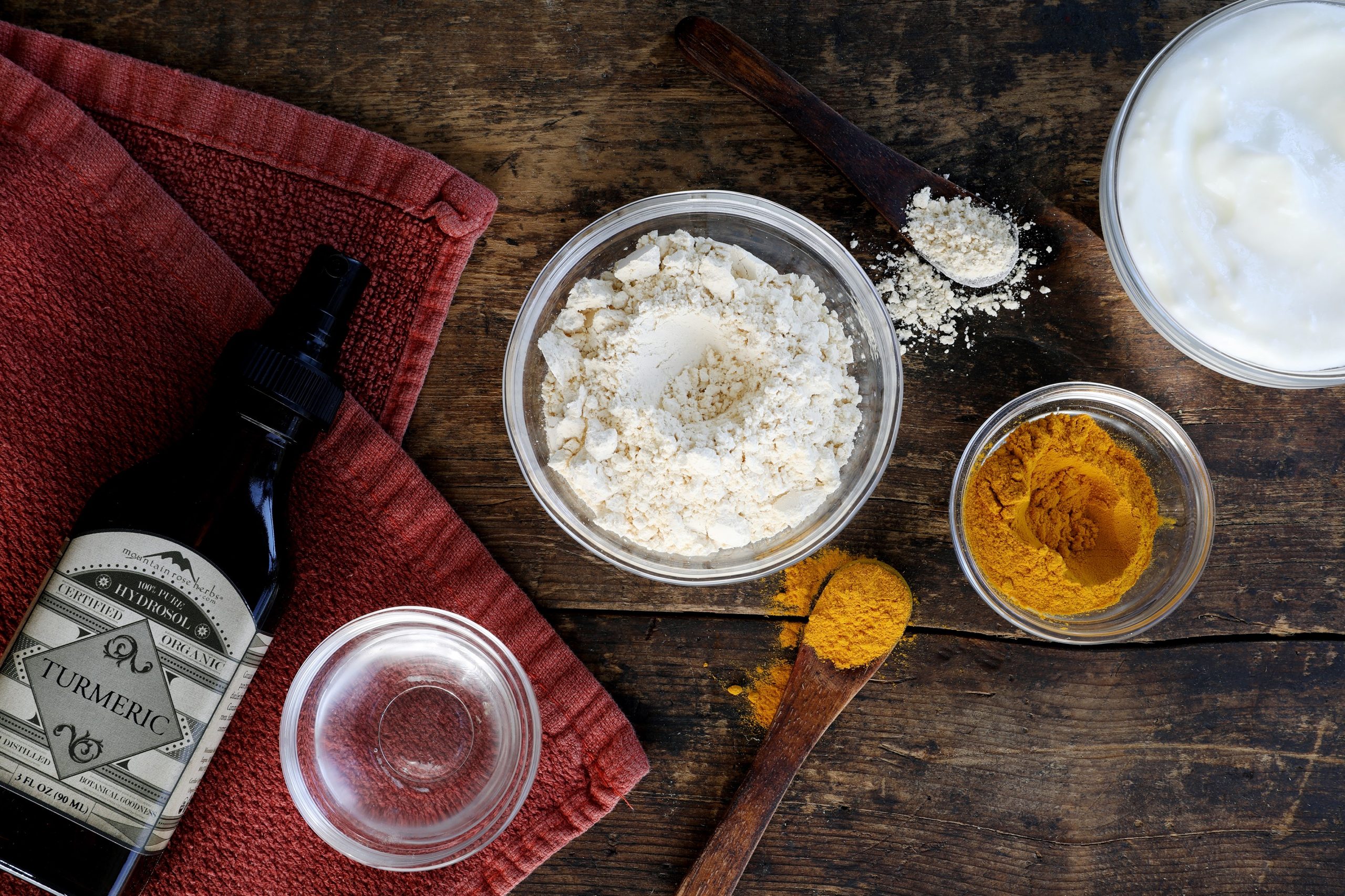 Glass bowls and wooden spoons containing ingredients ready to be assembled, arranged on a rustic wooden table.