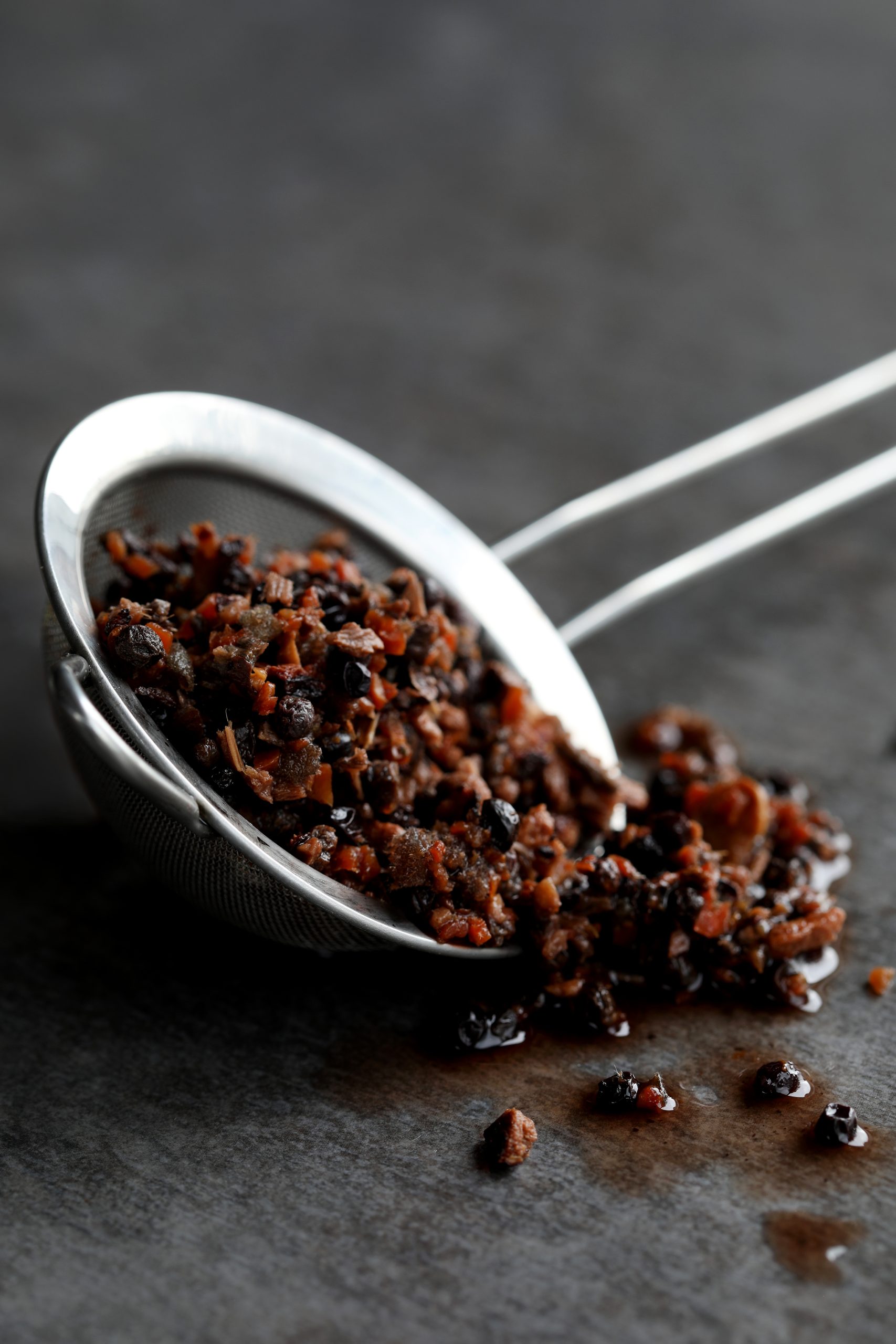 Metal strainer with wet botanicals spilling out. 