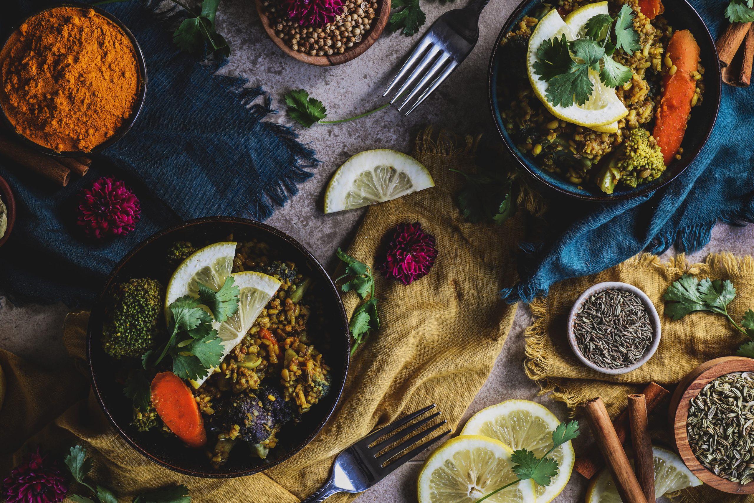 Two bowls of warming kitchari with ingredients around them