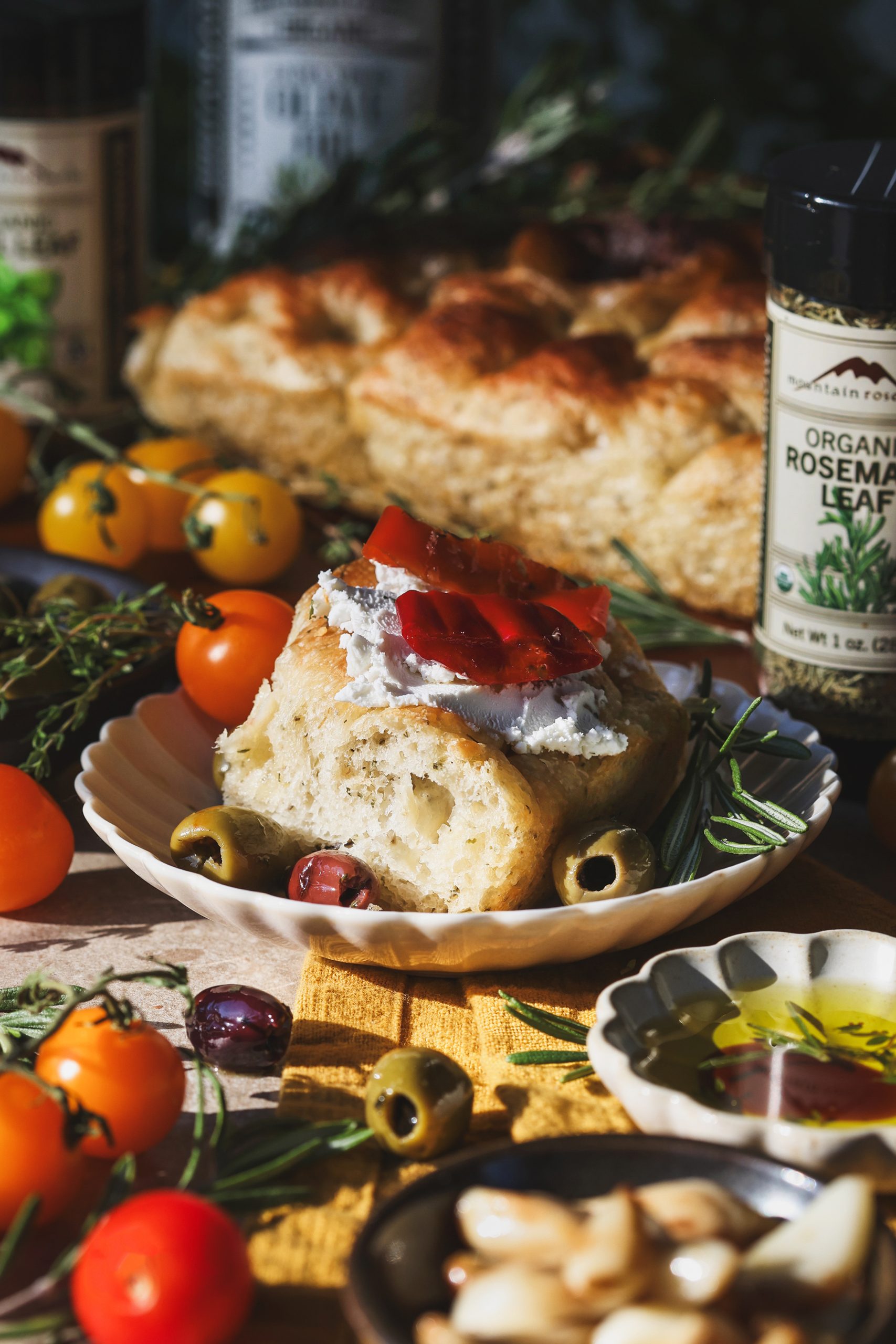 A slice of focaccia on a place topped with goat cheese and red peppers
