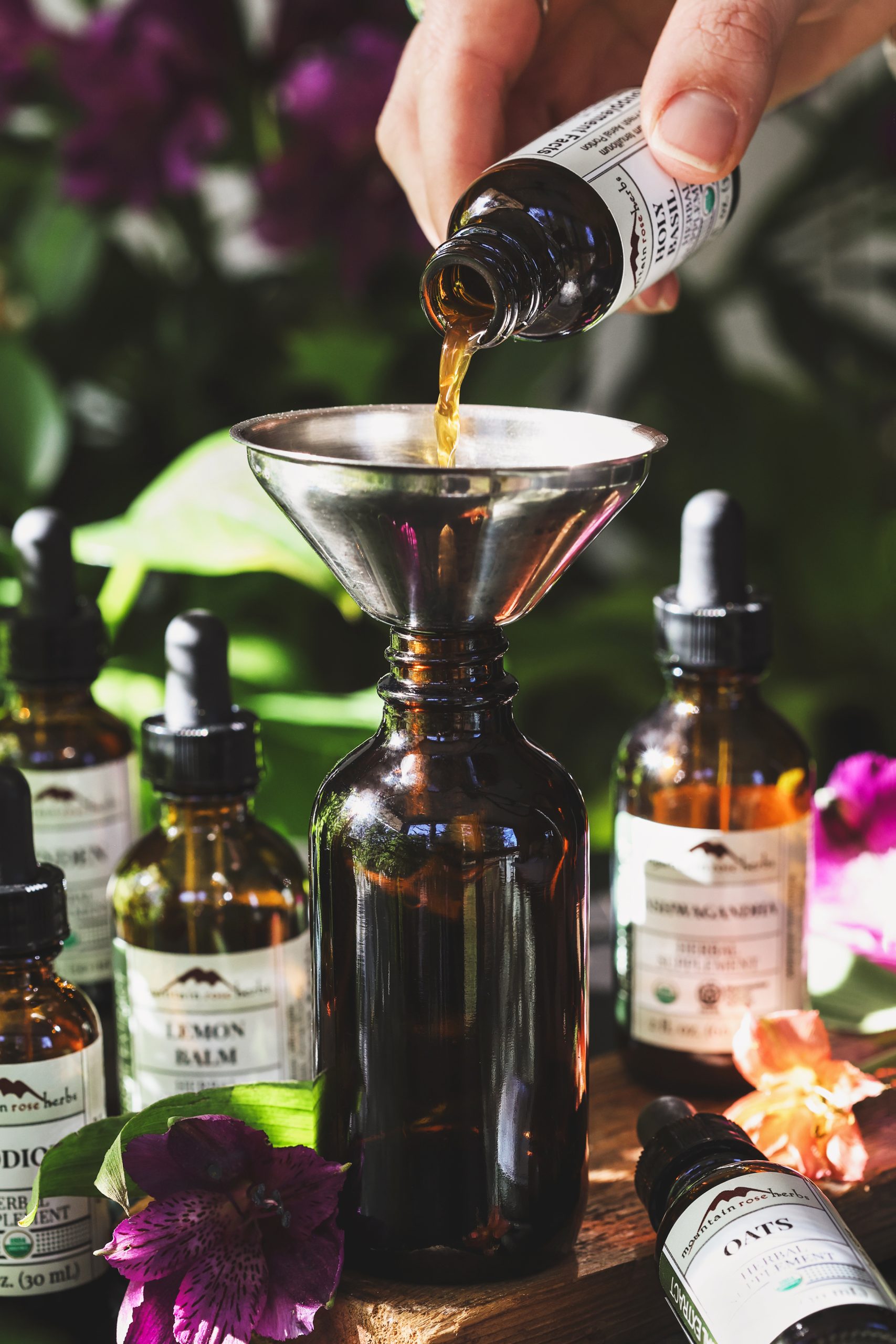 A photo of herbal extracts being poured into an empty bottle for mixing