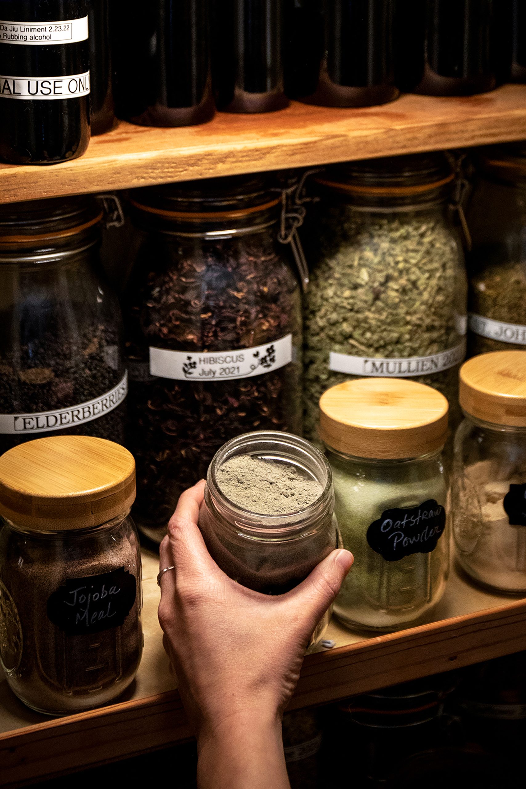 A photo of someone grabbing a jar out of a home apothecary