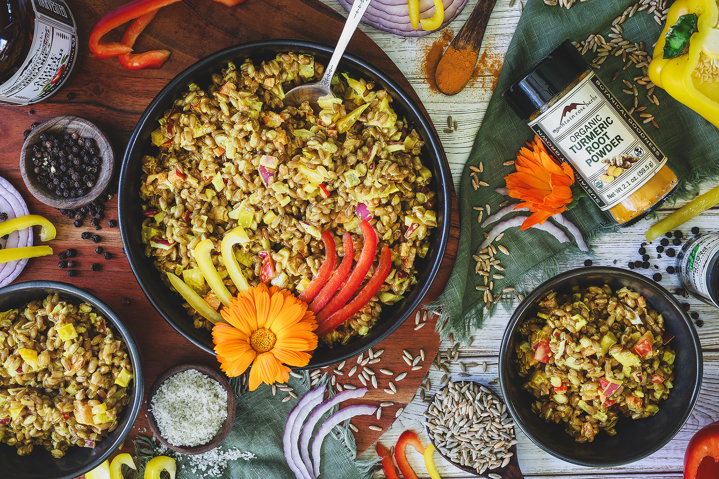 An overhead photo of rye berry salad in a bowl with flower garnish